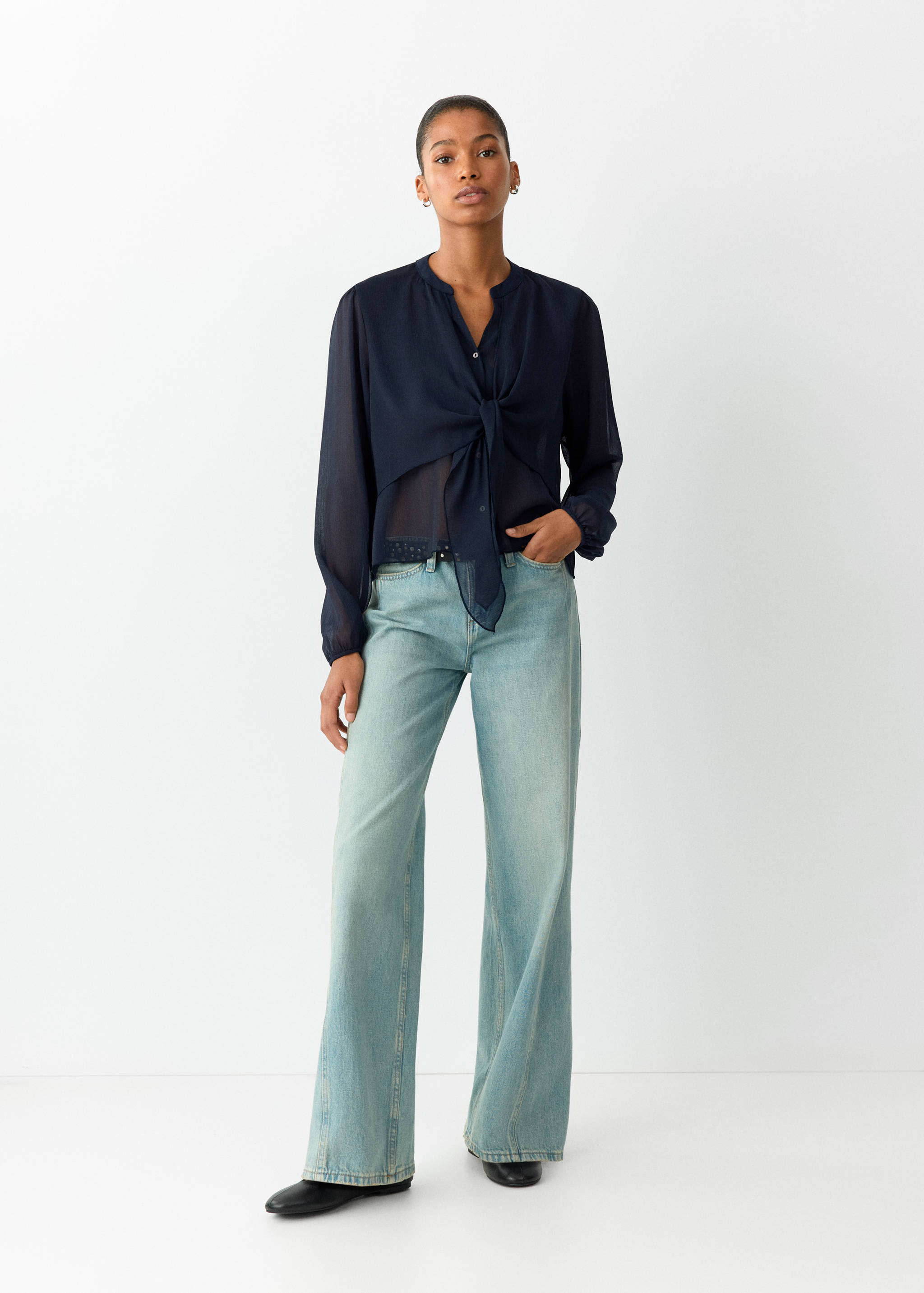Navy blue sheer blouse with mandarin collar and front knot, worn with blue jeans.