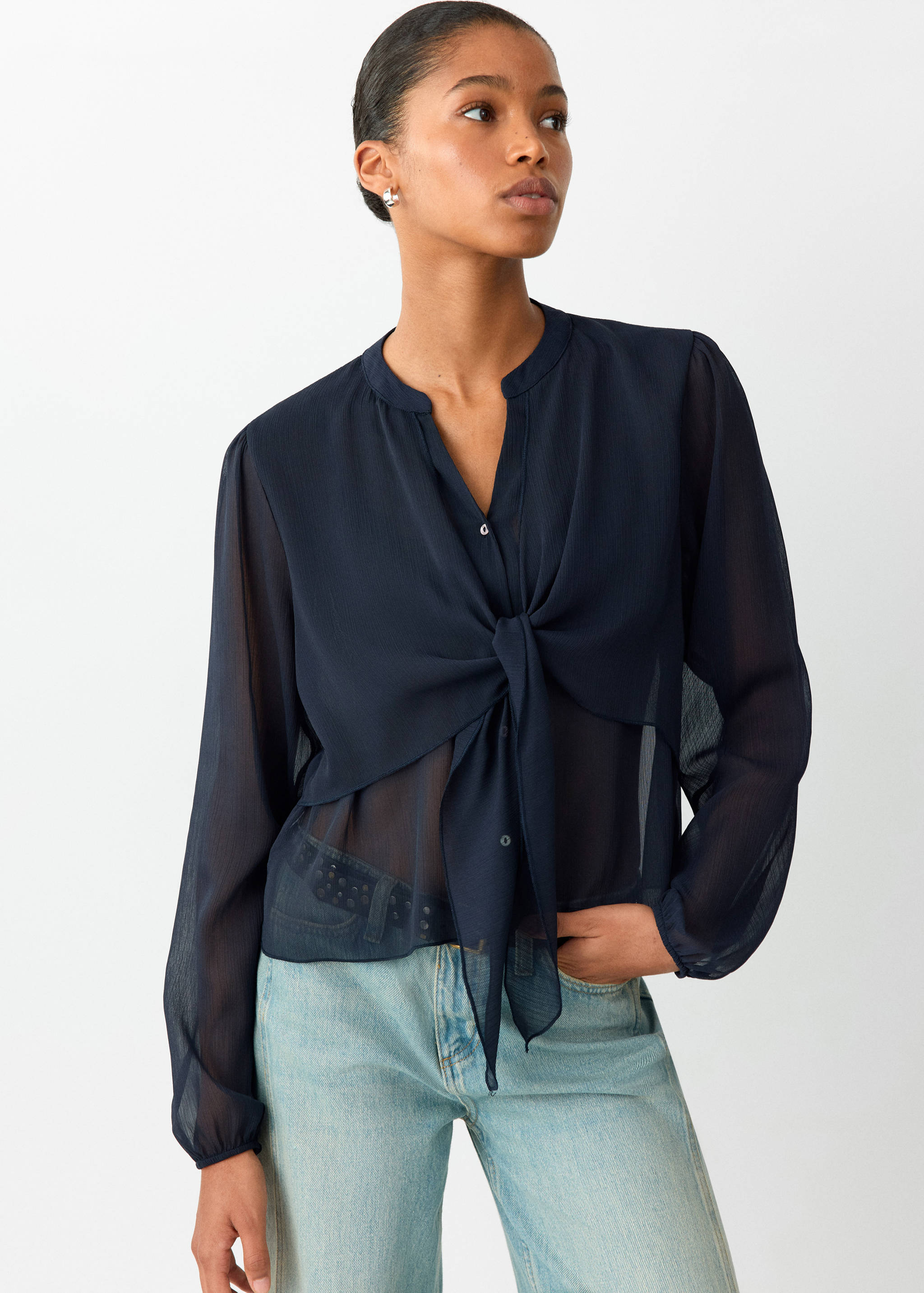 Navy blue sheer blouse with long sleeves, a banded collar, and a front tie knot.