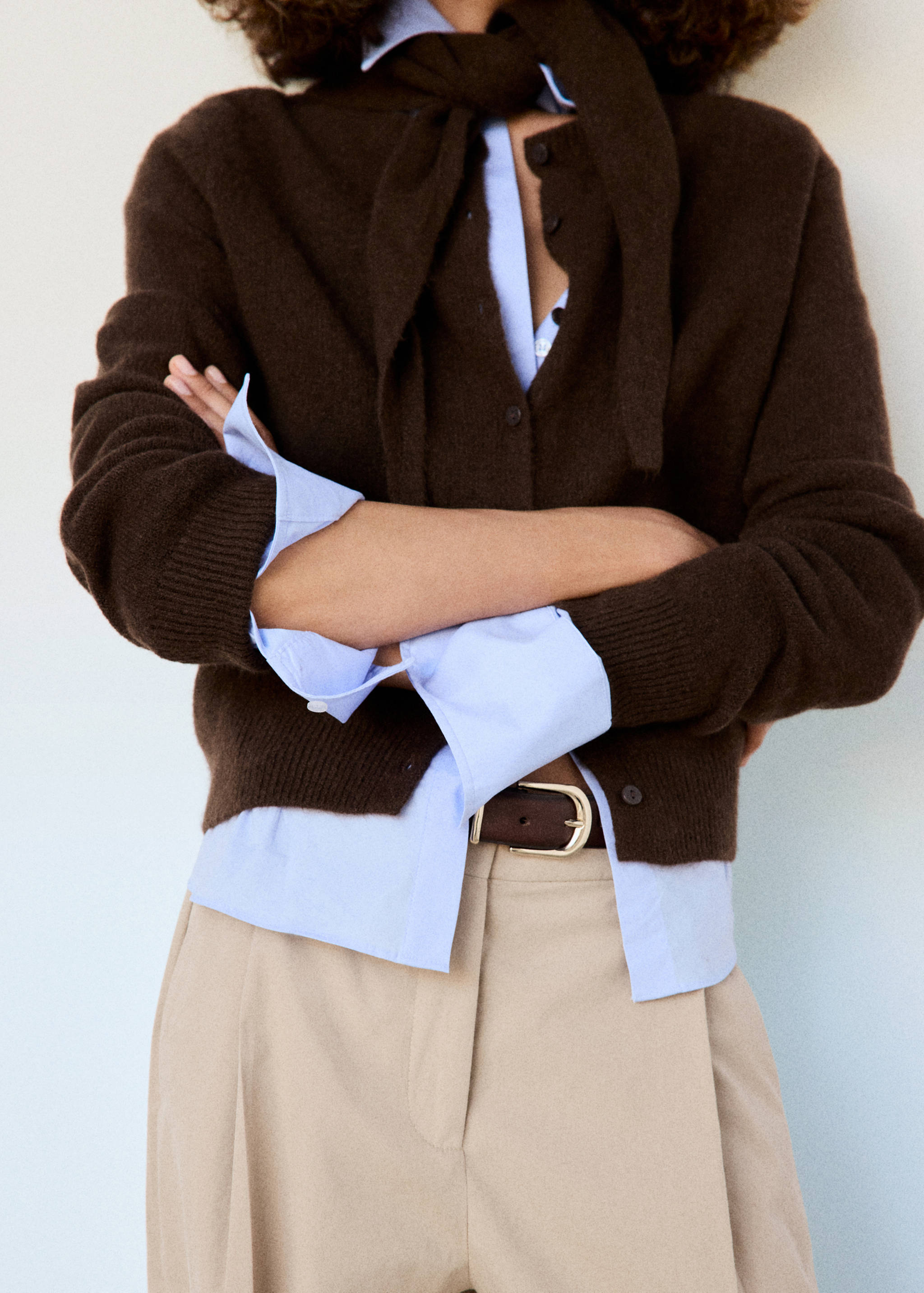 Dark brown knitted button-up cardigan worn over a light blue shirt with a sweater tied around the neck.