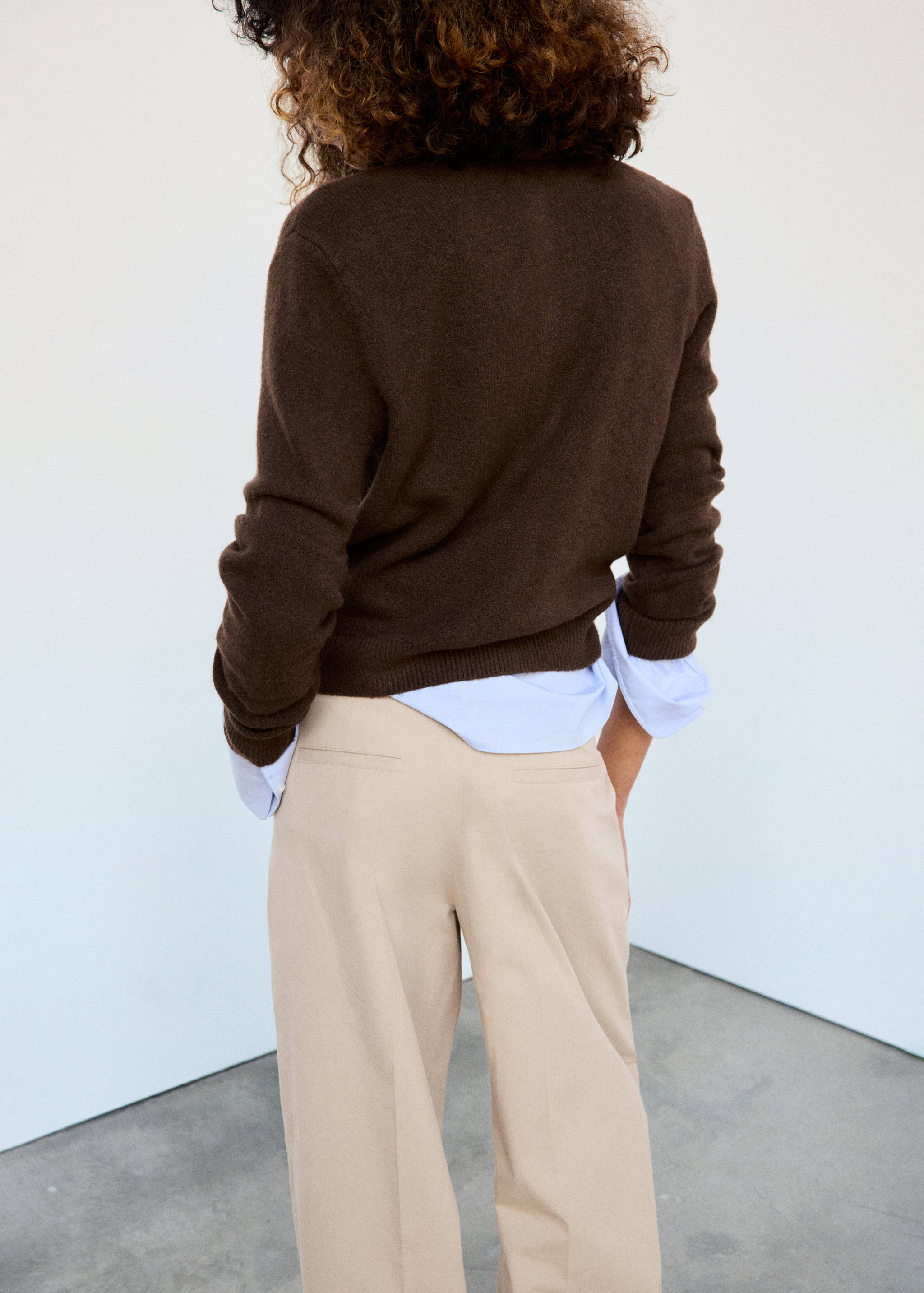 Dark brown knitted cardigan shown from the back, layered over a blue shirt.