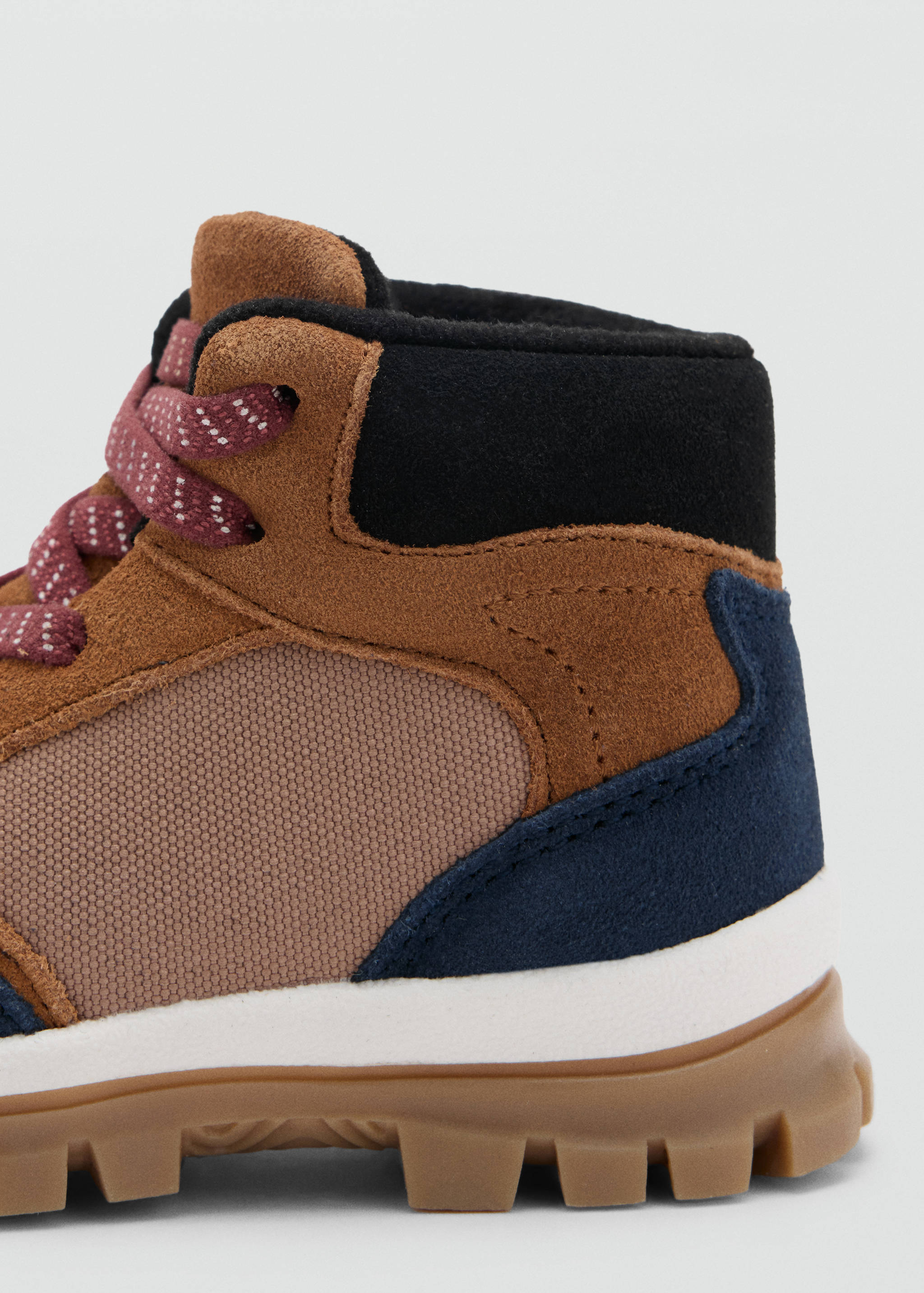 Close-up of a kids' multi-panel boot with brown suede and a chunky gum sole.