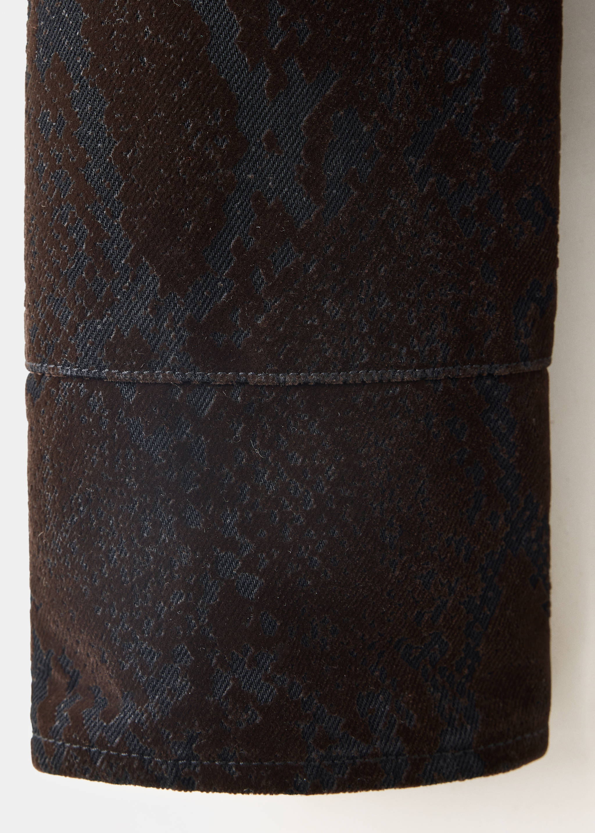 Brown jacket fabric close-up with a dark patterned velvety texture.