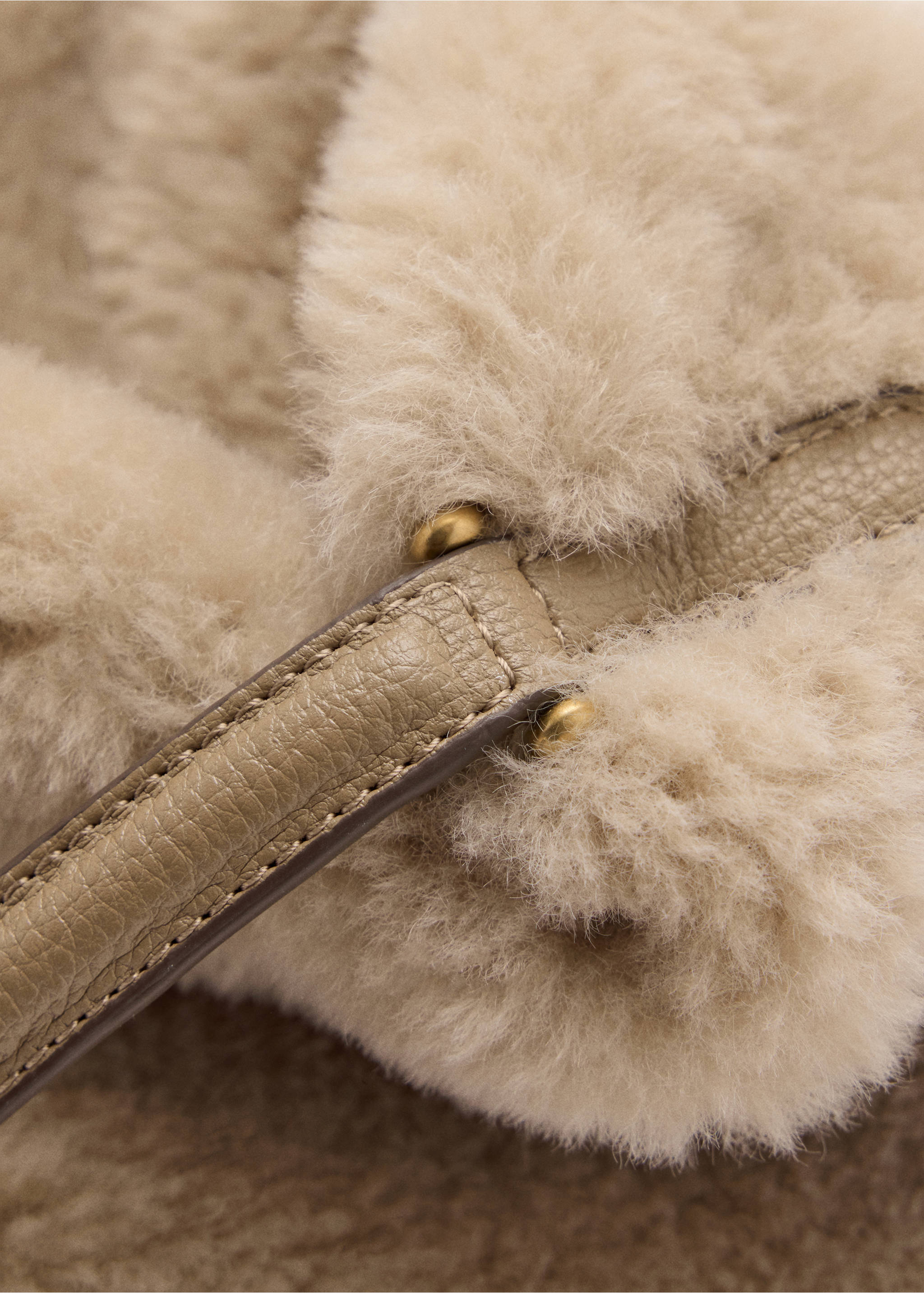 Detalle de bolso saco de efecto pelo en beige con asa de piel texturizada y tachuelas metálicas en tono dorado., Beige. Ref: 37037798-00.