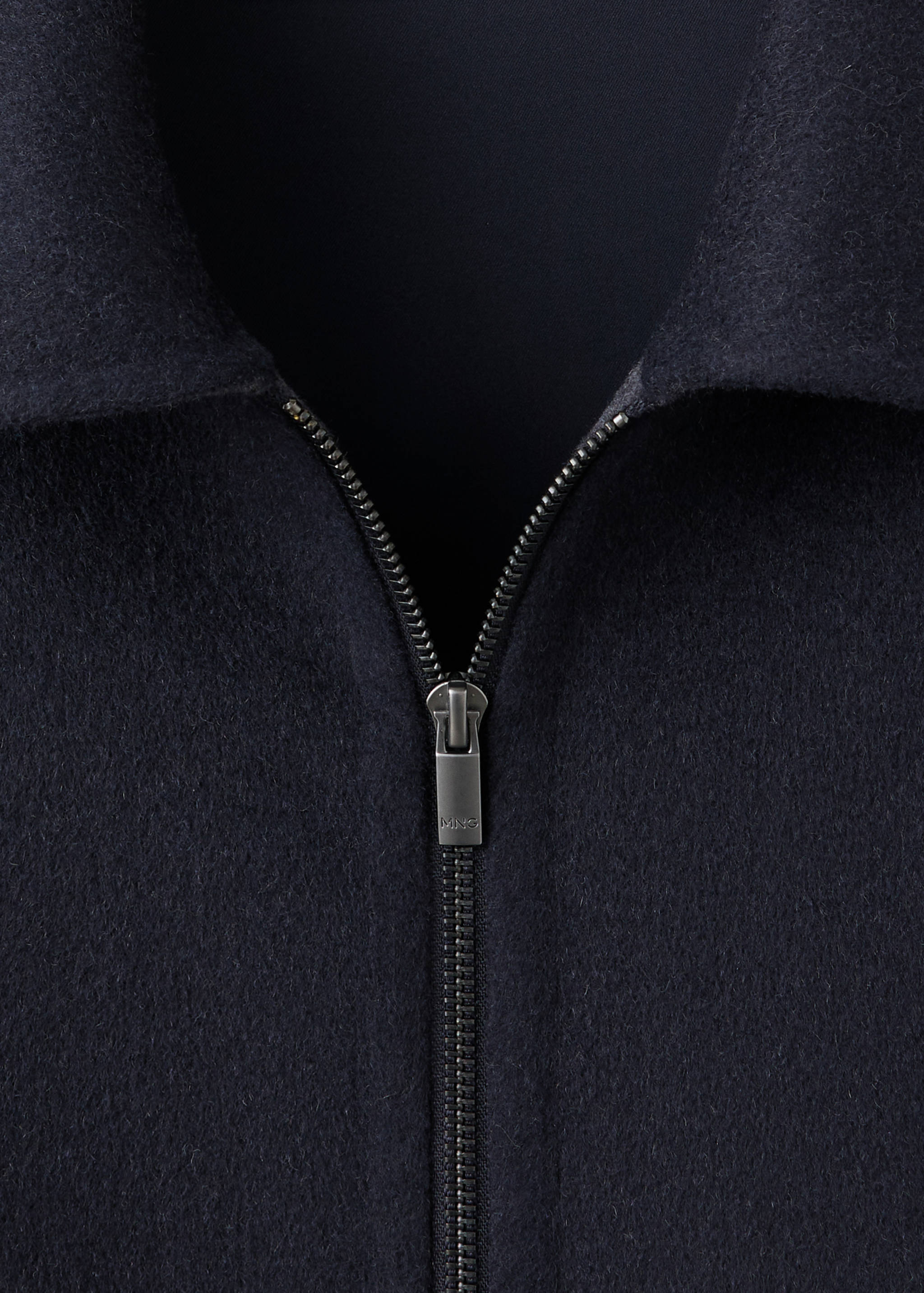 Navy blue jacket close-up, featuring a pointed collar and a silver metal zipper.