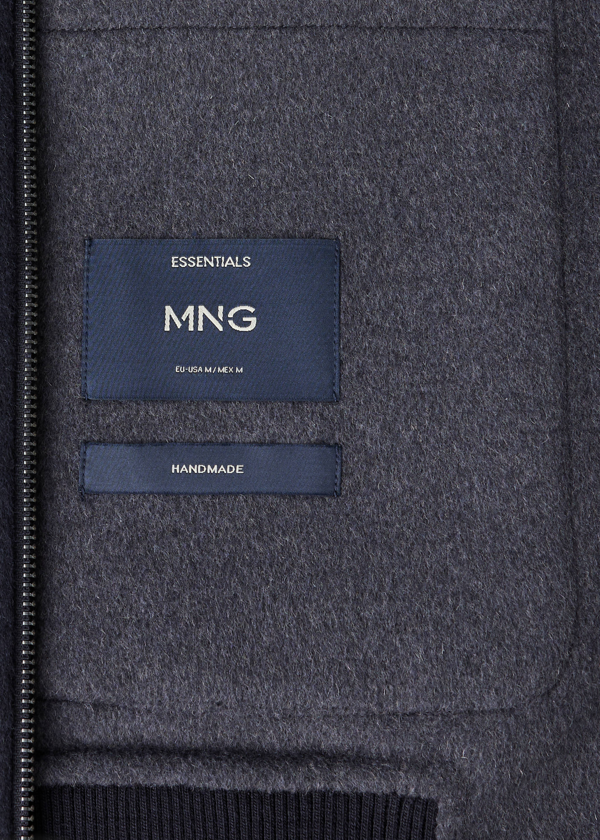 Close-up of dark charcoal grey jacket interior featuring MNG and Handmade labels.