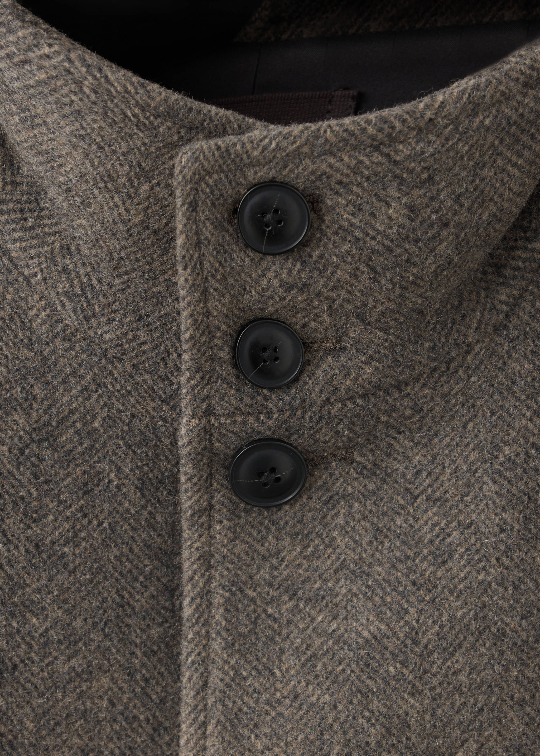 Brown herringbone coat button detail.