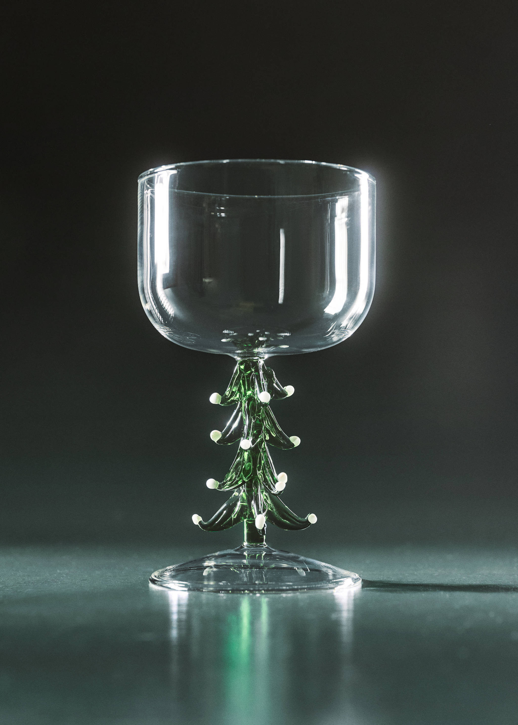 Clear glass goblet with a decorative green Christmas tree stem adorned with white dots.