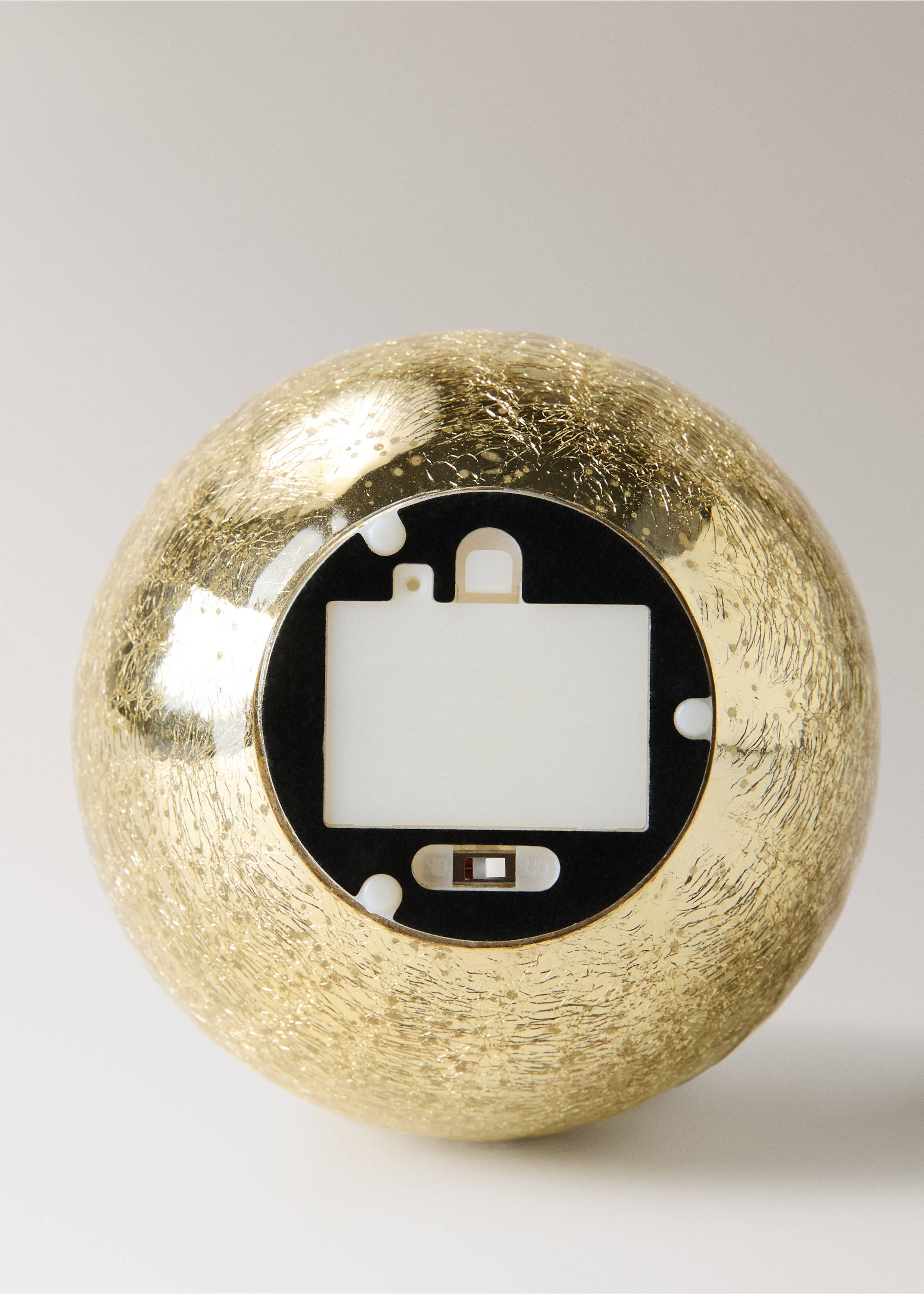 Detail of the battery compartment on the bottom of a spherical gold Christmas ornament., Gold. Ref: 37037895-00.
