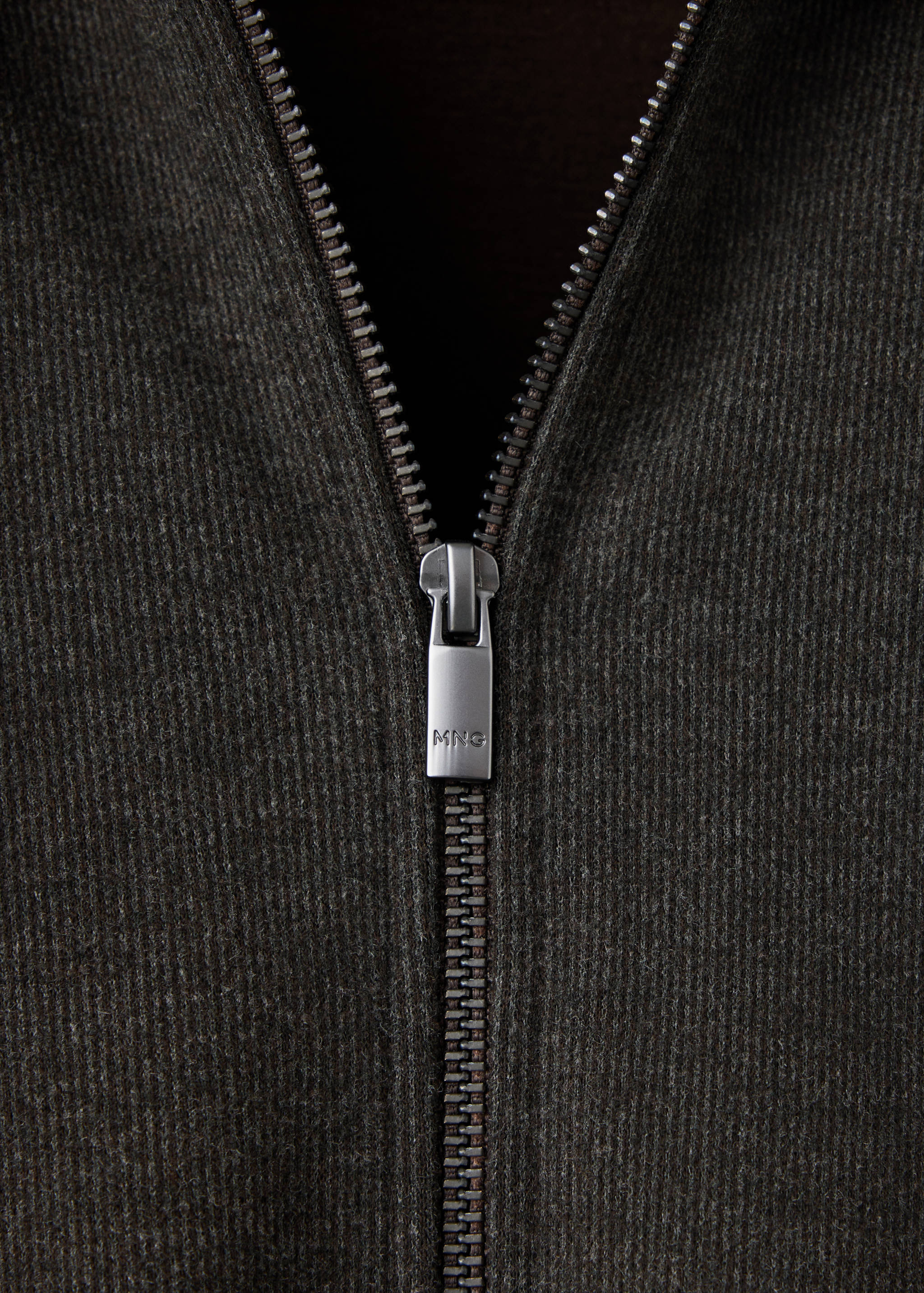 Close-up of the silver metal zipper on a dark grey sweatshirt.