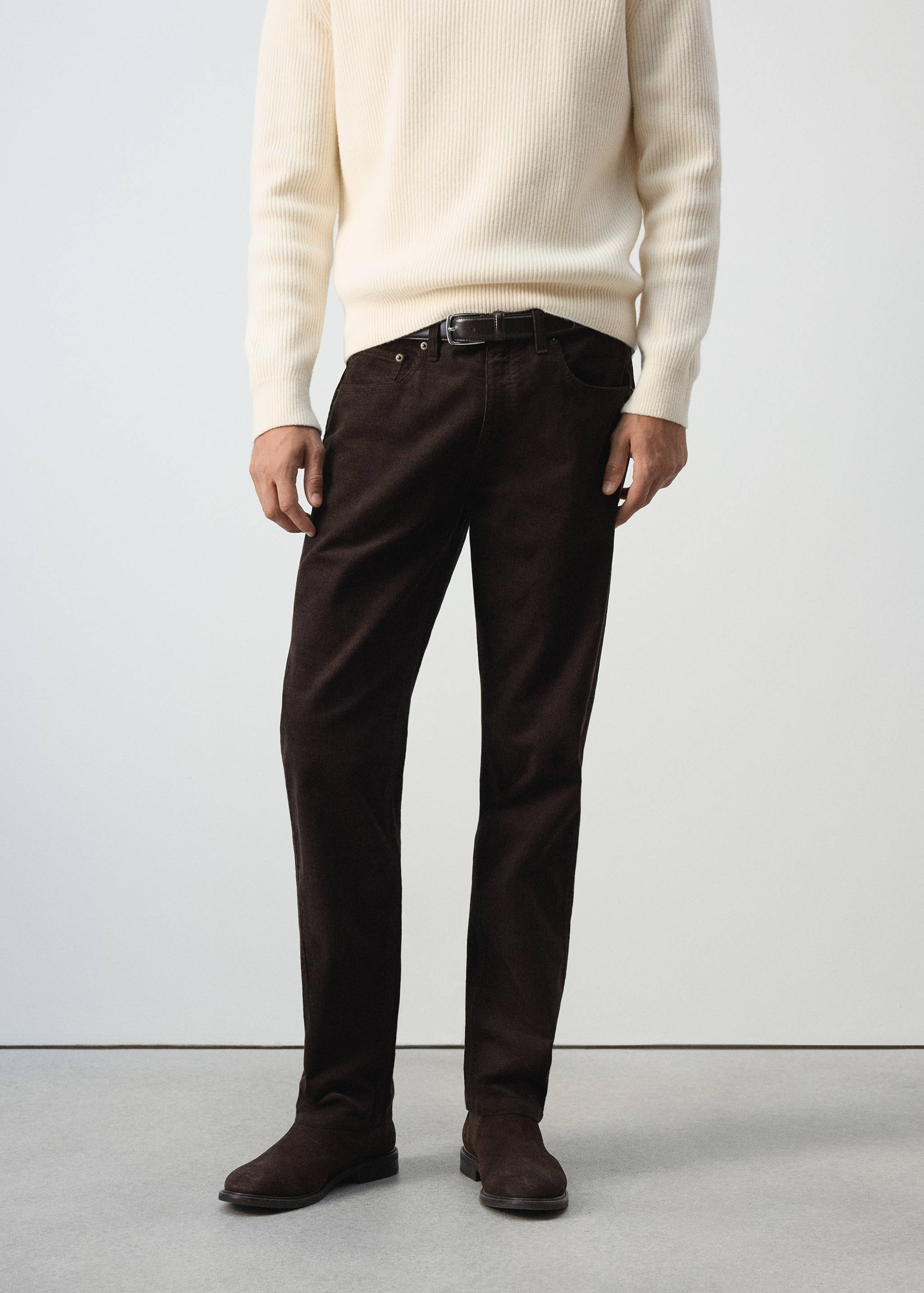 Dark brown trousers worn with a cream ribbed knit sweater and brown shoes.