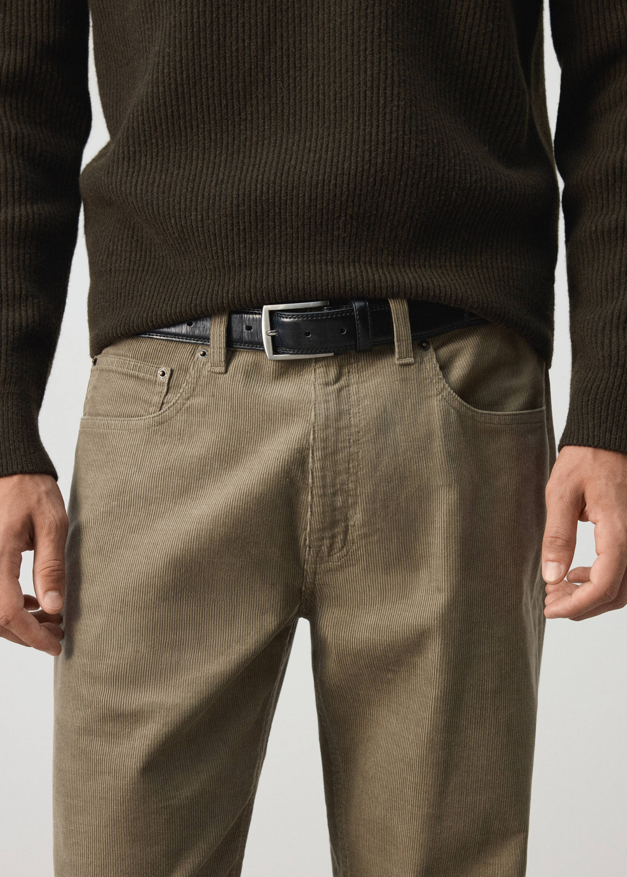 Olive-green corduroy trousers styled with a black leather belt and dark olive ribbed knit sweater.
