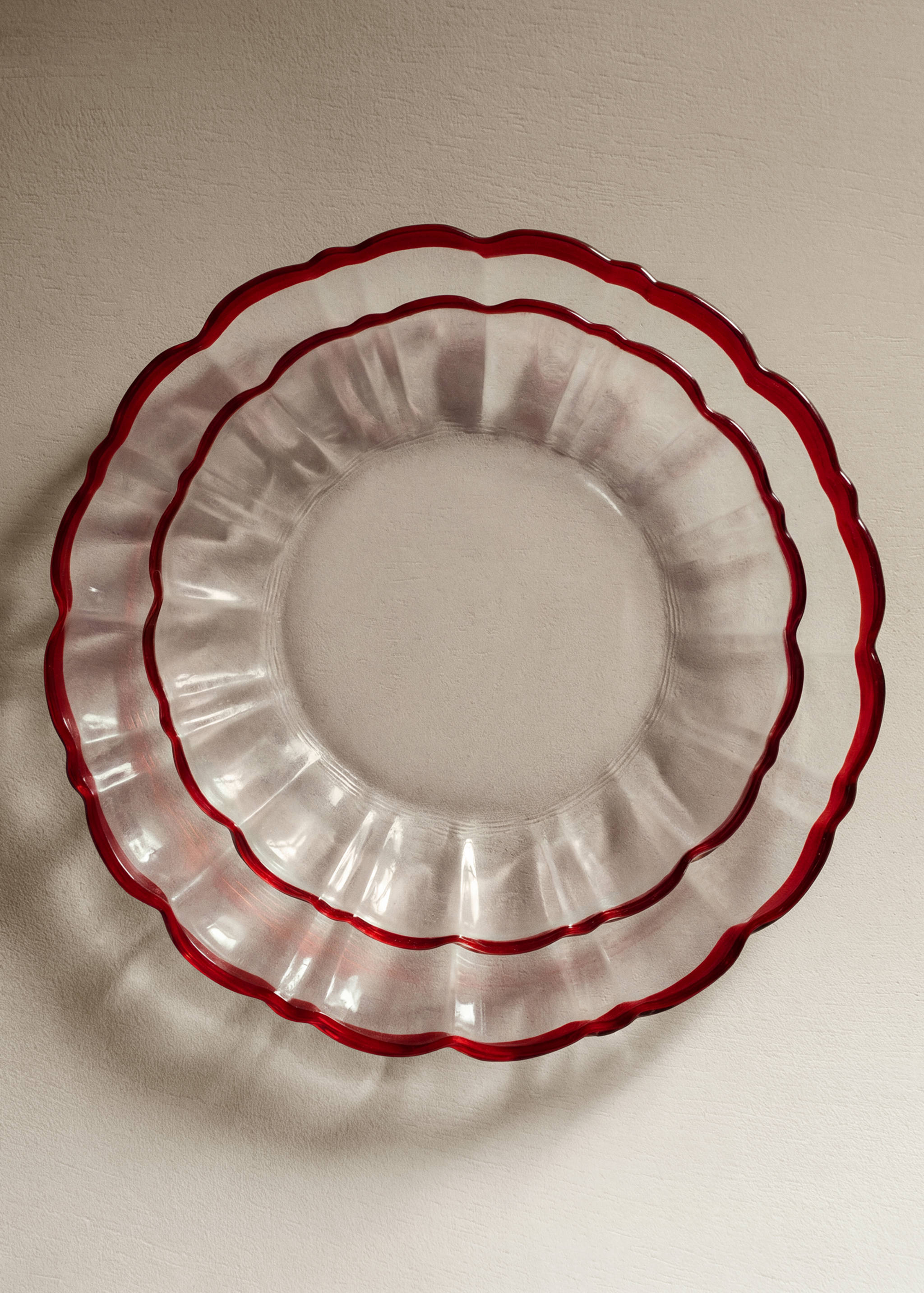 Clear glass plates with fluted rims and bold red edges.