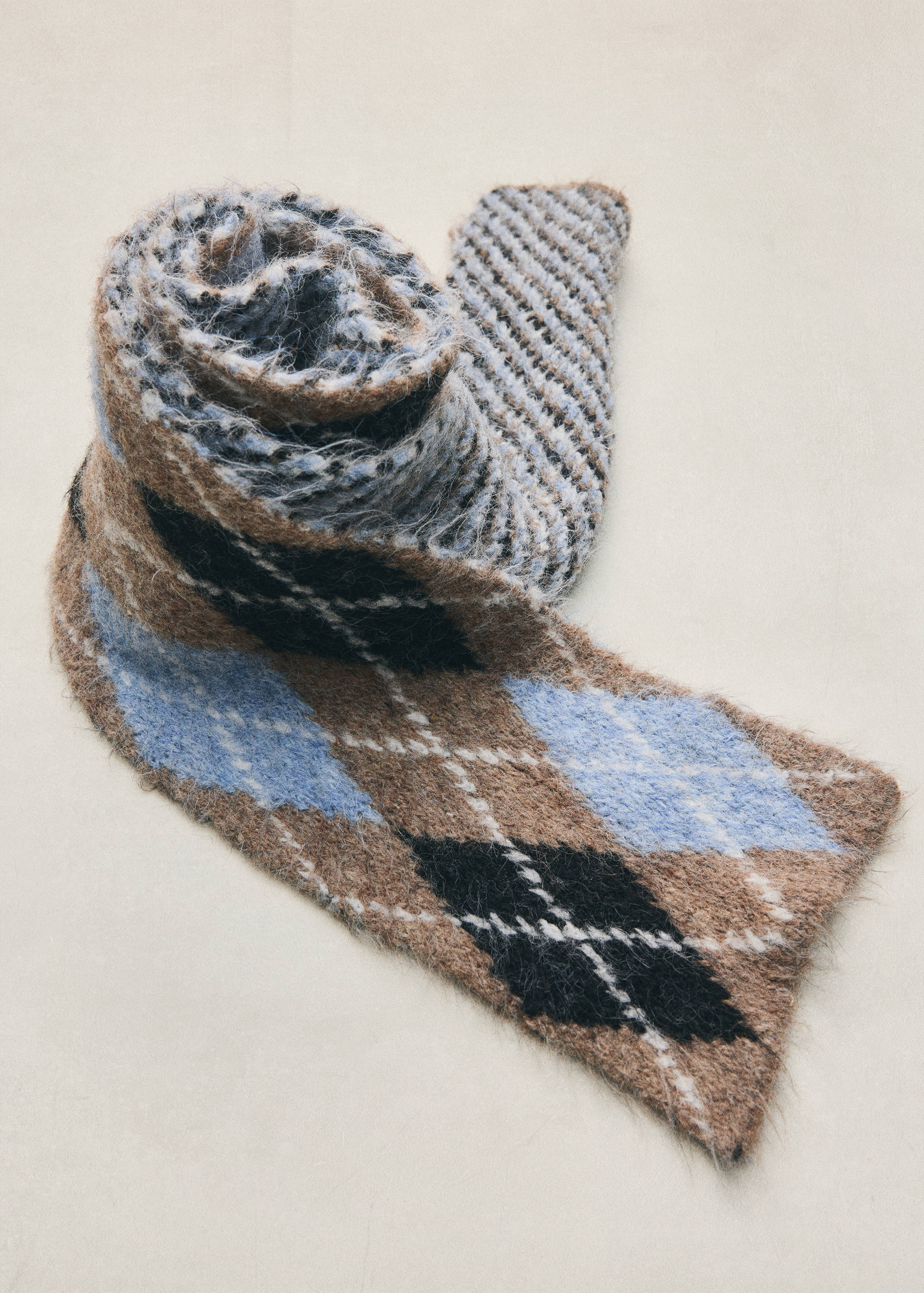 Bufanda de punto con estampado de rombos en tonos marrón, azul y negro.