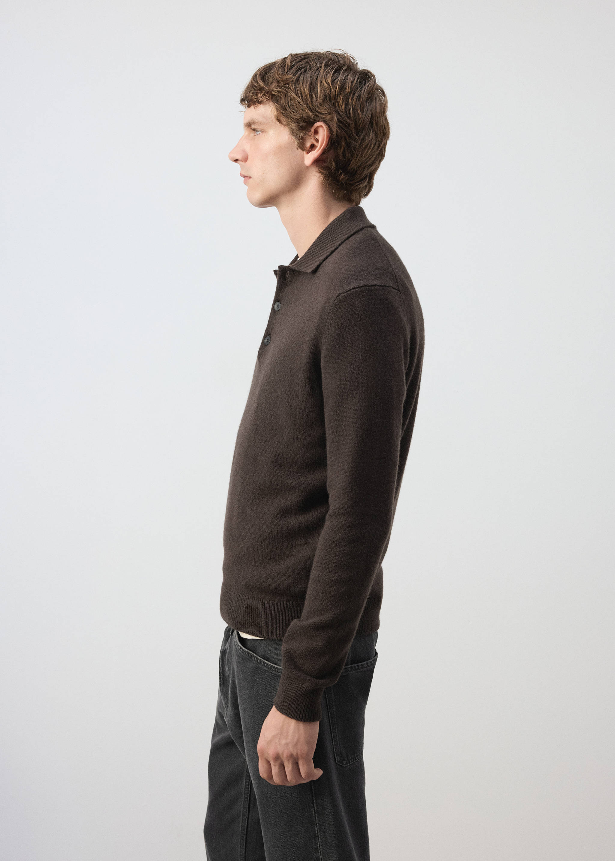 Polo de punto de manga larga en marrón oscuro con tapeta de botones, combinado con pantalón oscuro.