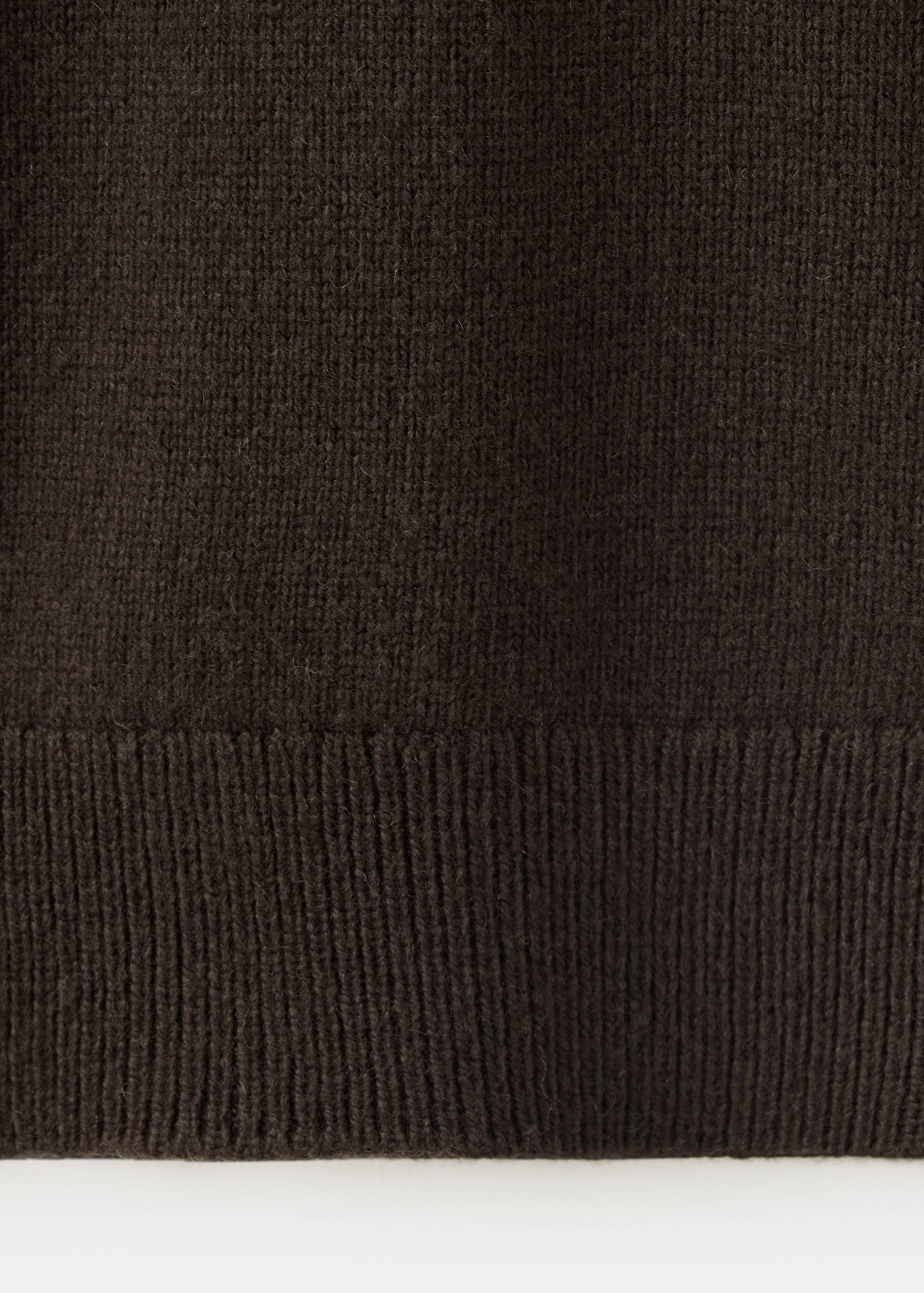 Primer plano de la textura del tejido del polo marrón oscuro y el dobladillo de canalé.