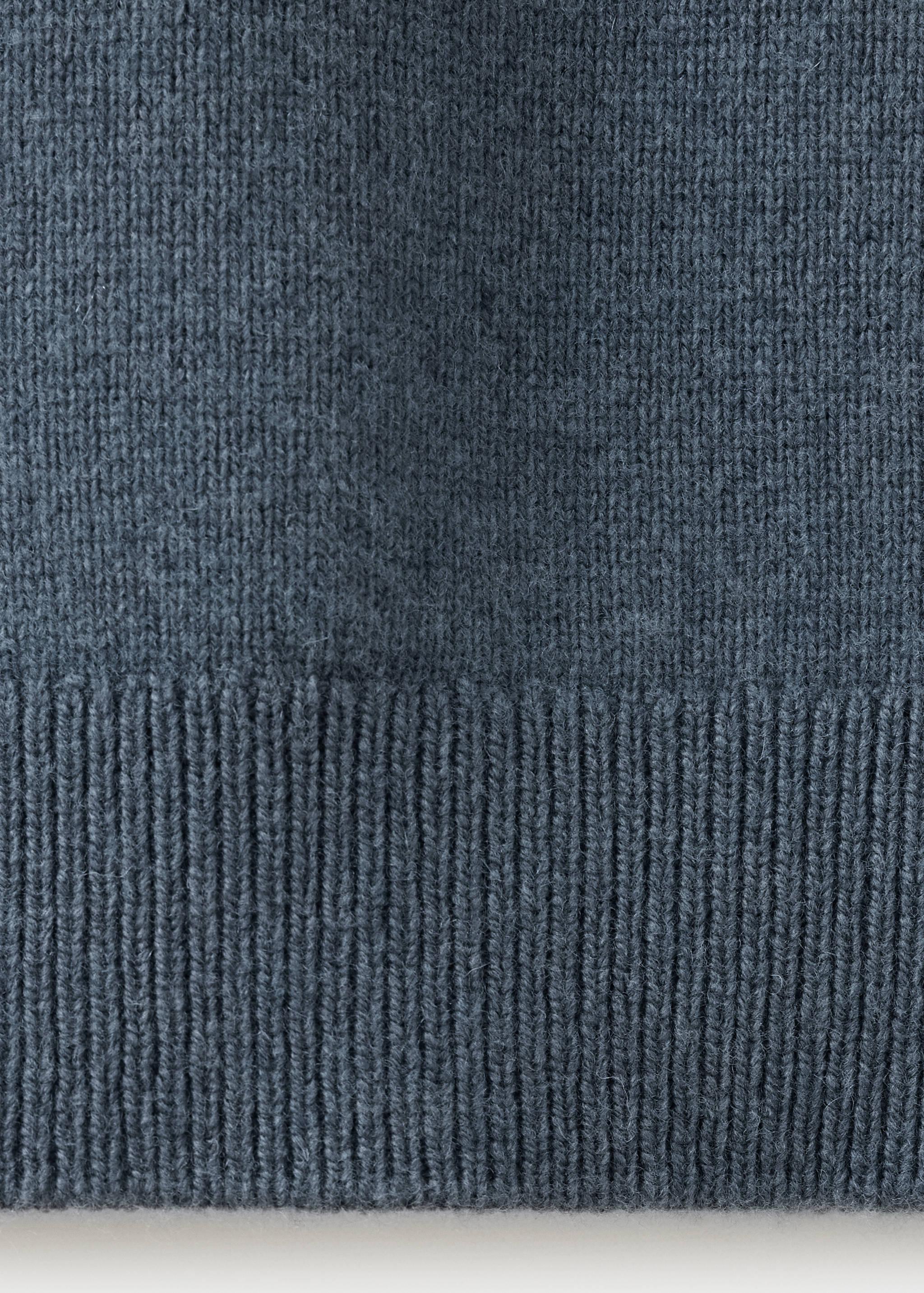 Detalle del polo azul grisáceo de punto fino que muestra el canalé texturizado.