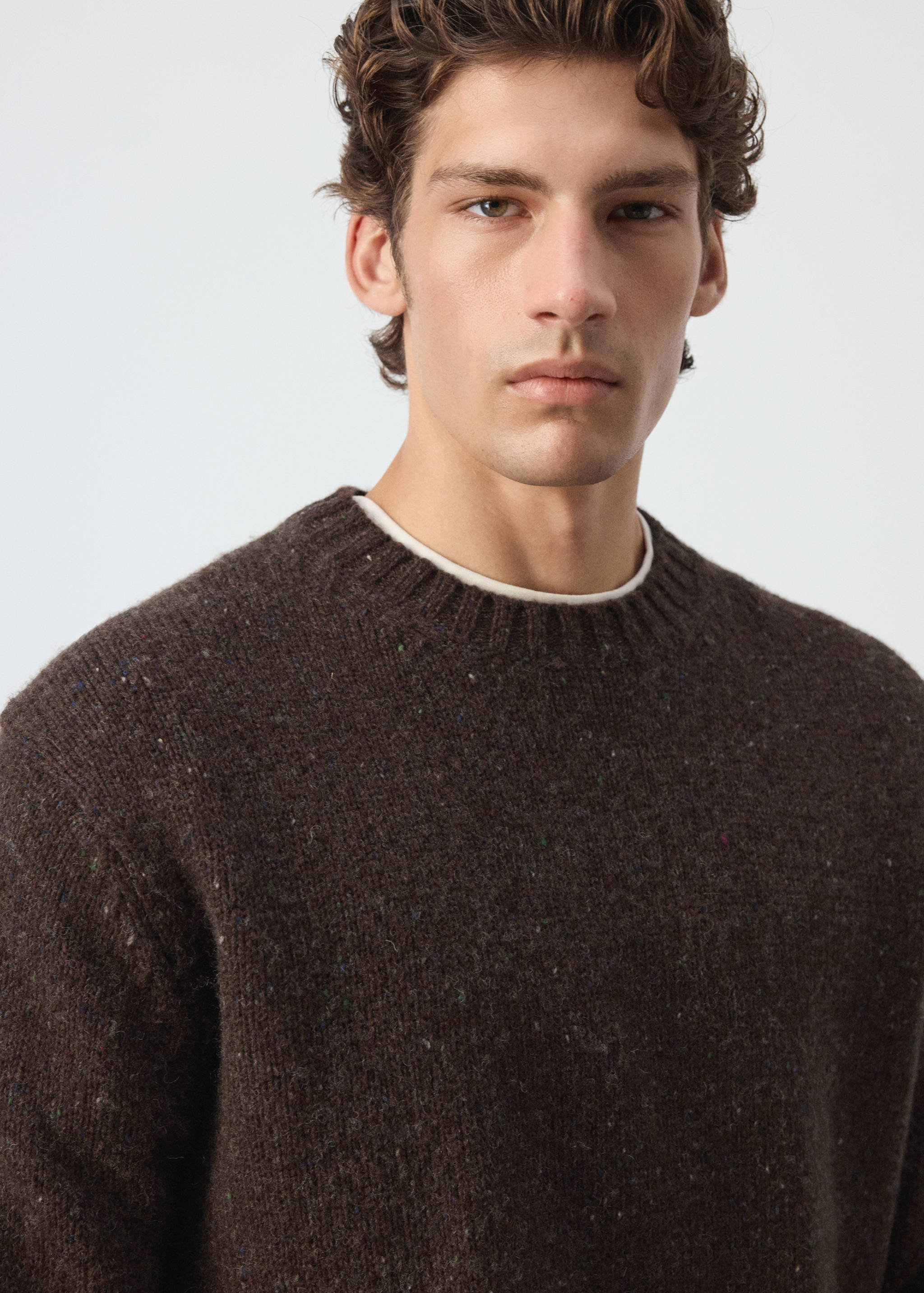 Close-up of a dark brown speckled crew neck jersey on a model.