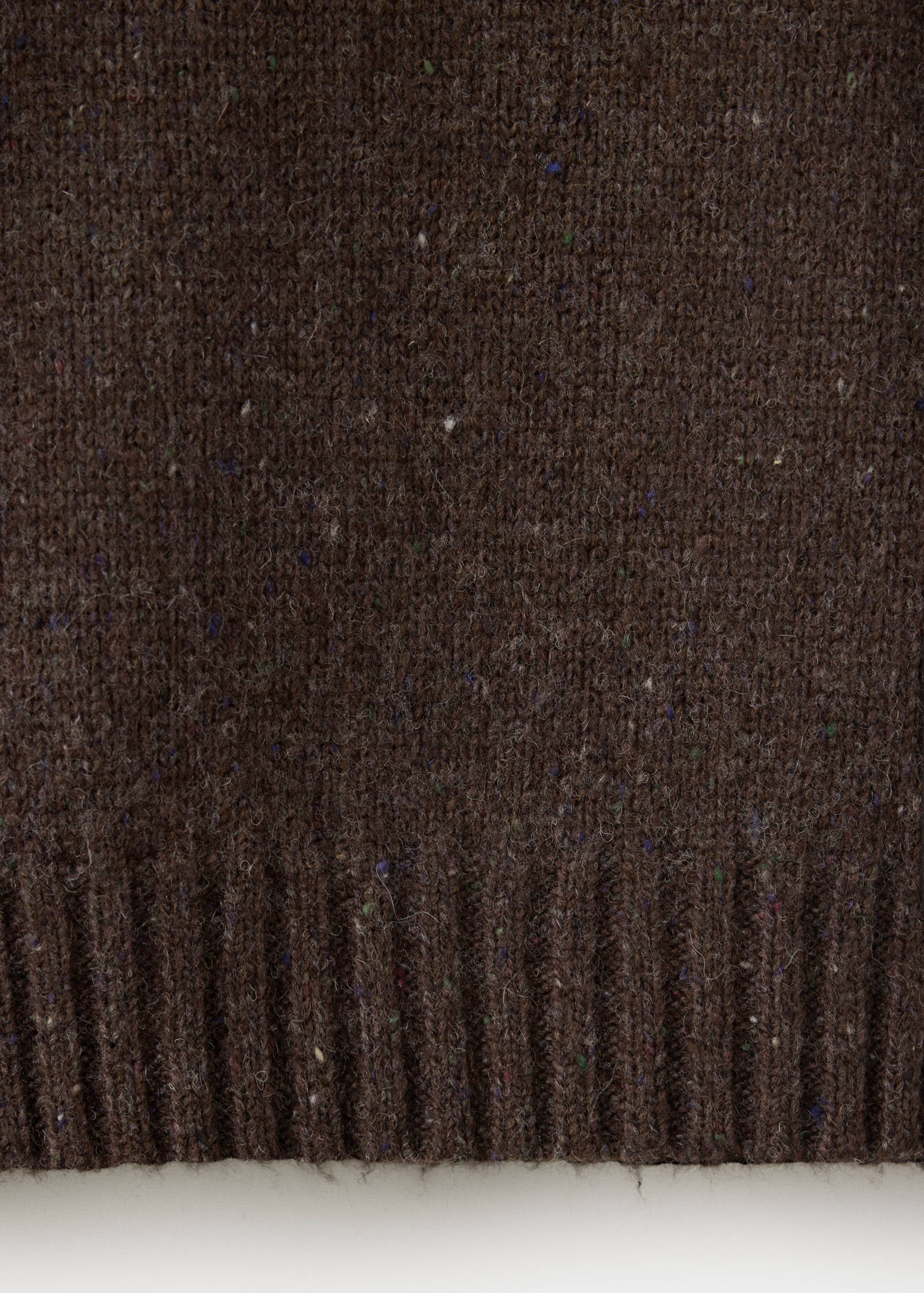 Close-up of a brown knit jumper fabric showing texture and ribbed hem.