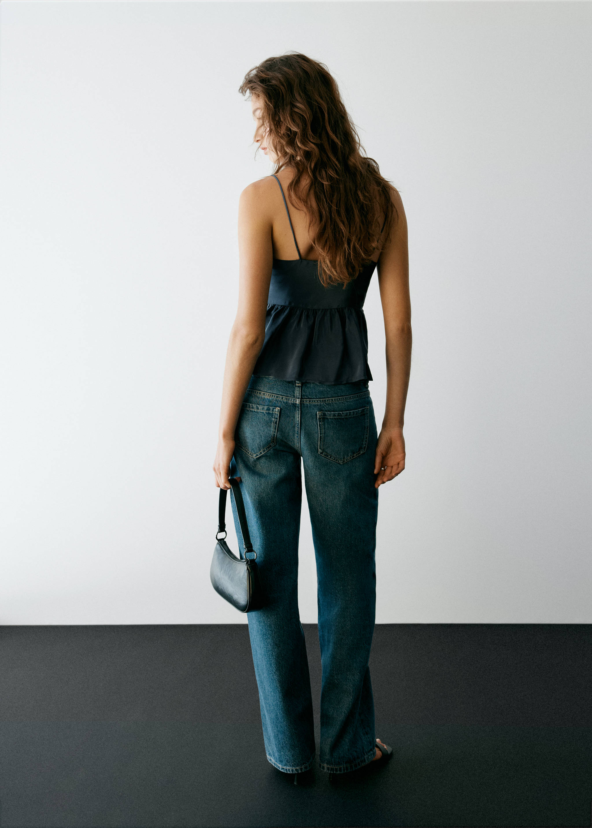 Dark blue camisole top with thin straps and peplum hem, back view.