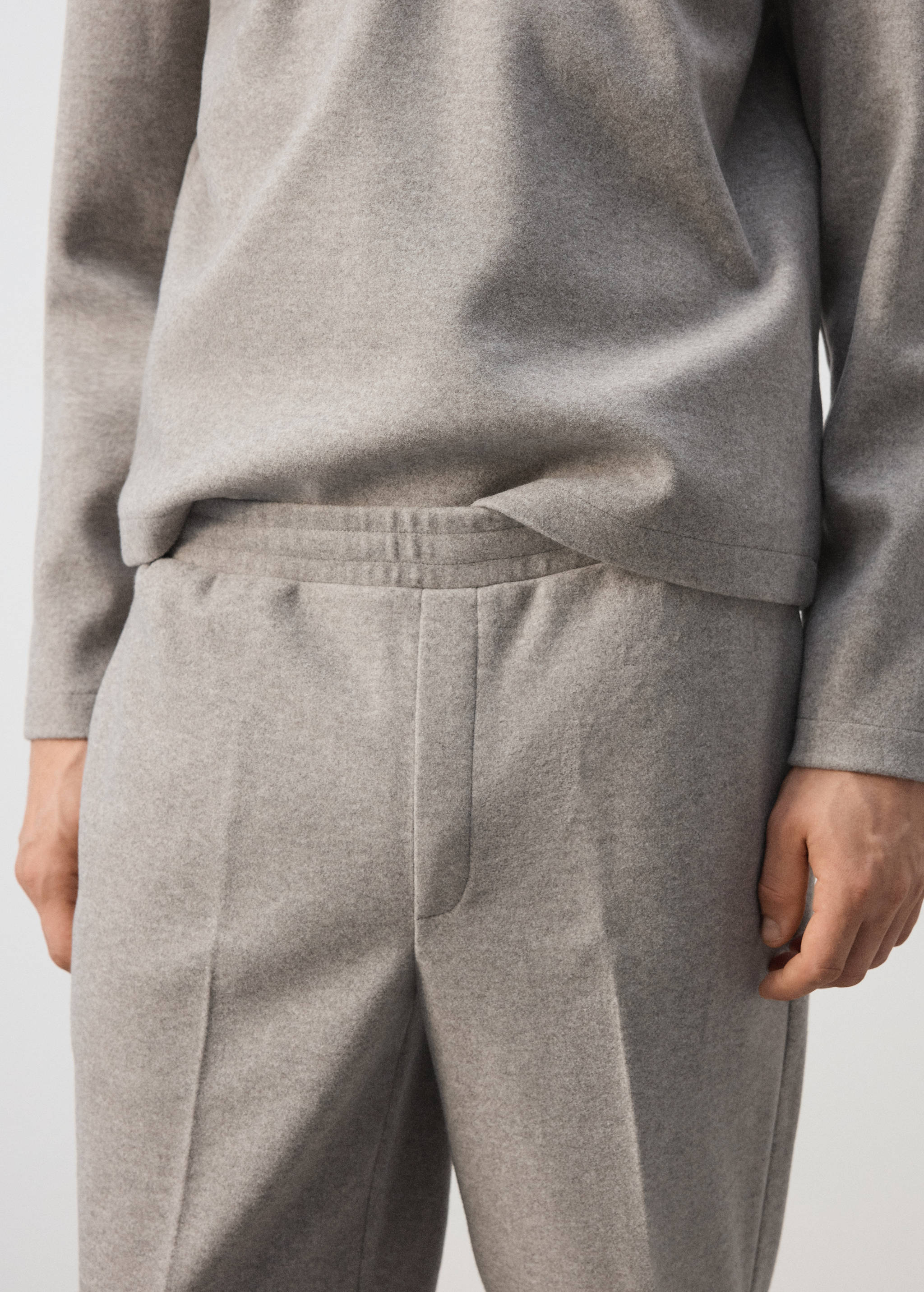 Light grey joggers featuring an elasticated waistband and pressed creases.