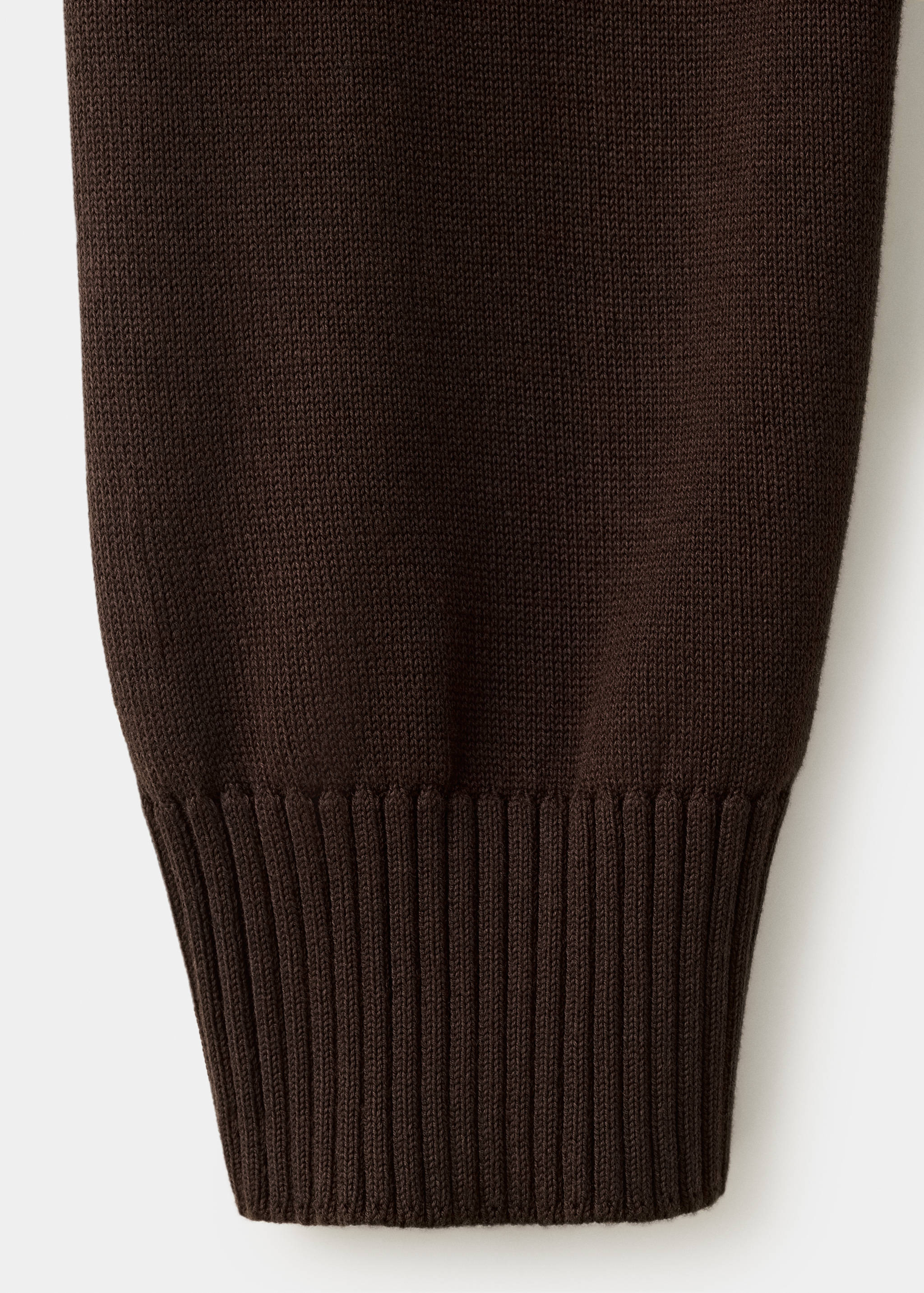 Close-up of a dark brown knit jumper sleeve with a ribbed cuff.