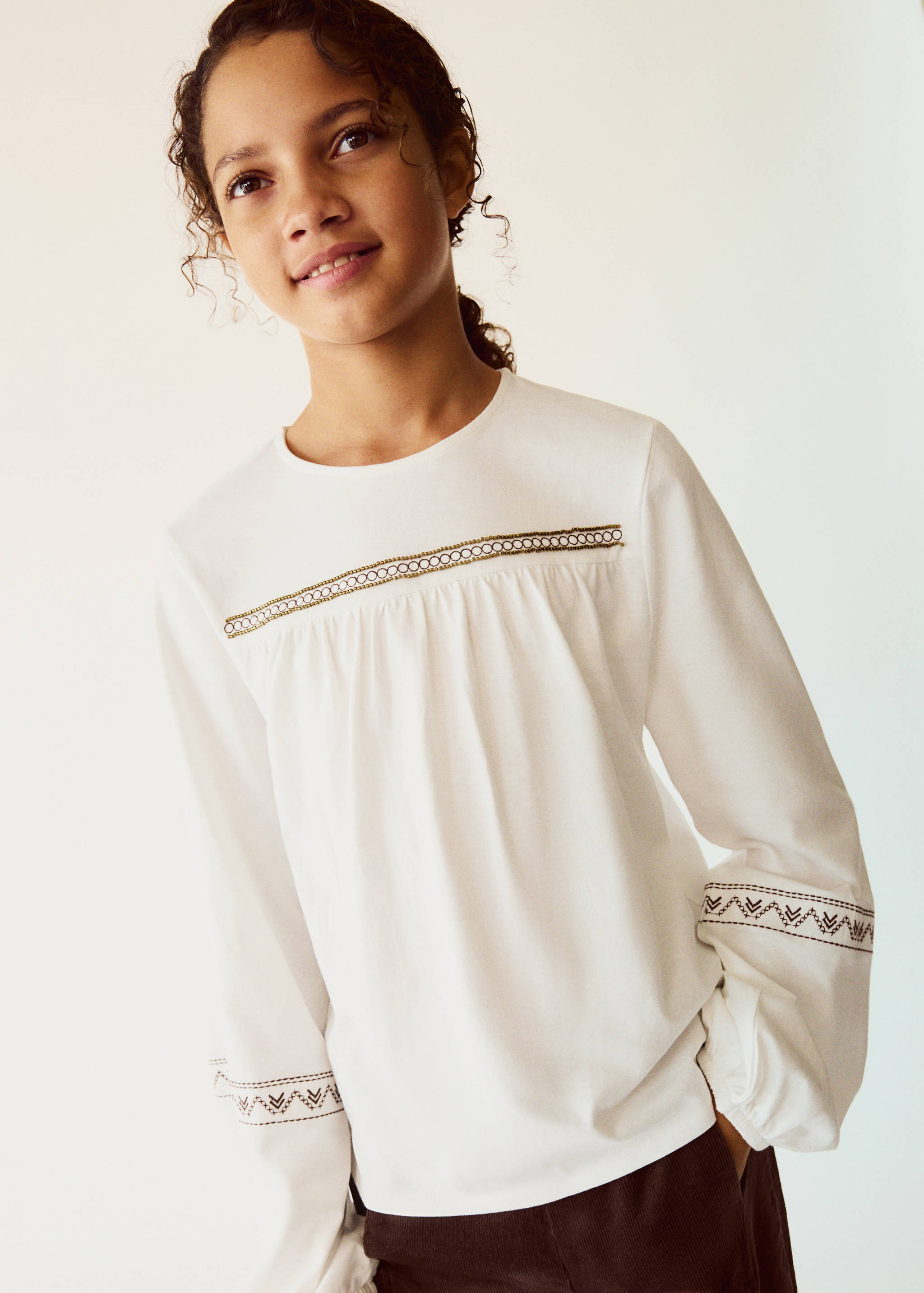 Off-white long-sleeve t-shirt with metallic chest embroidery.