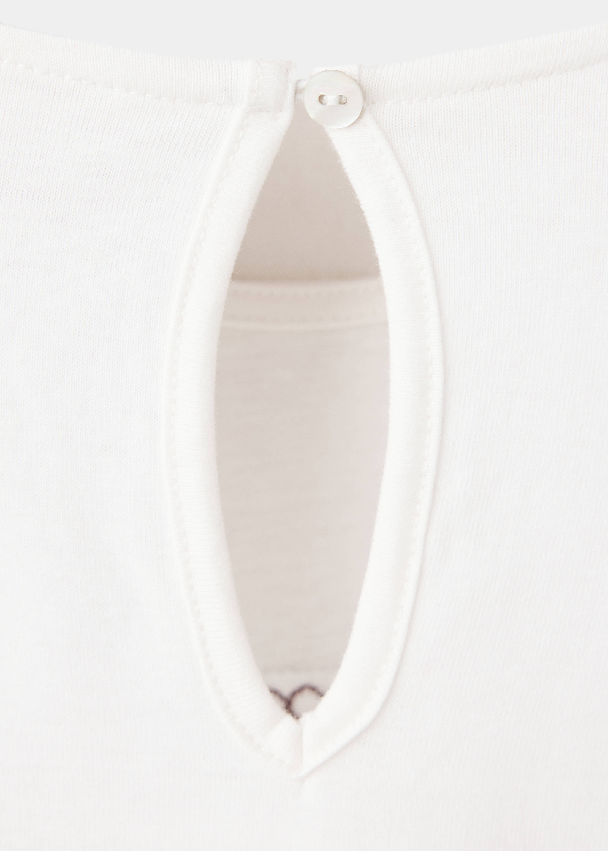 White kids' t-shirt fabric detail with a buttoned keyhole neckline.