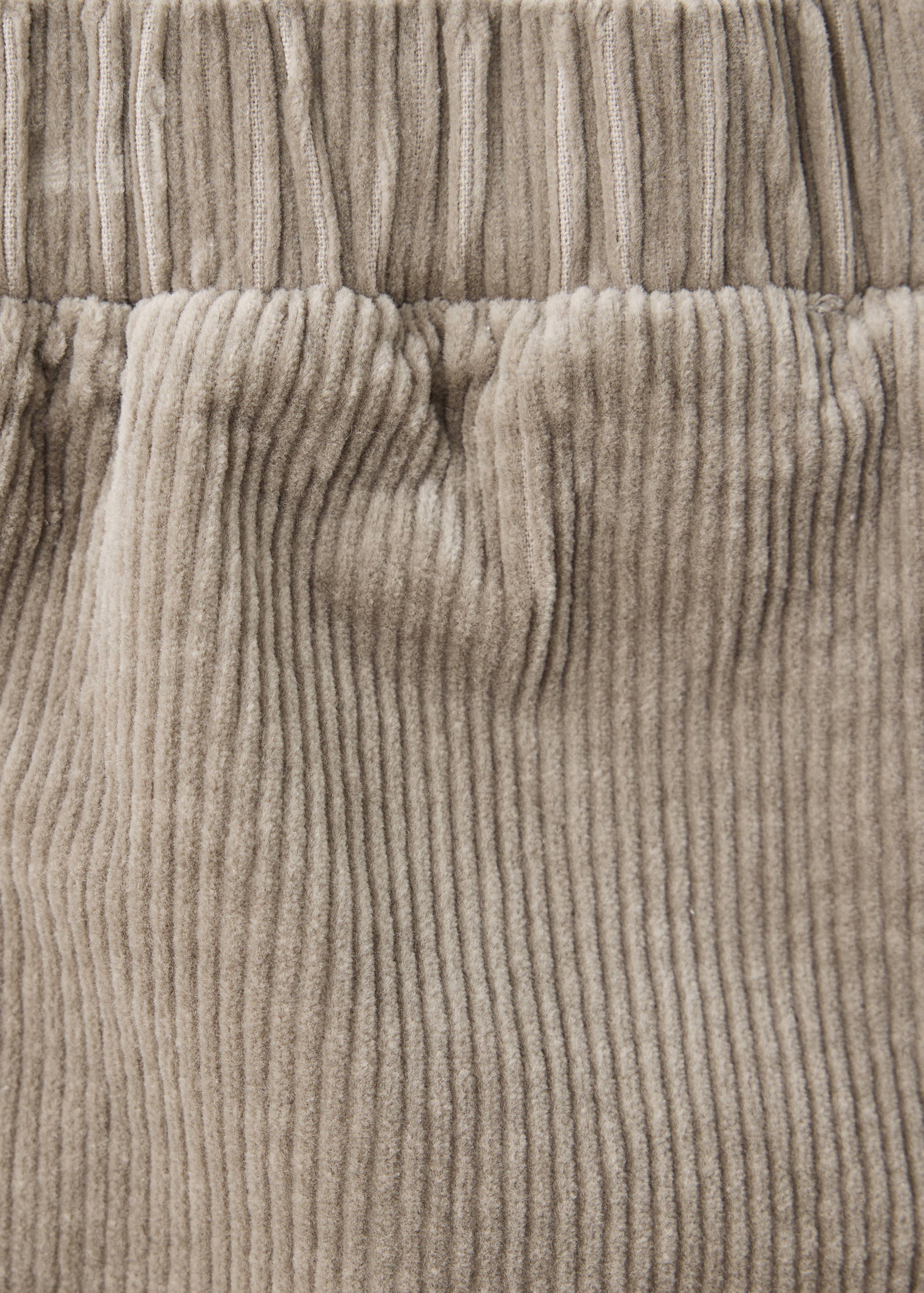 Beige corduroy fabric detail of children's trousers.
