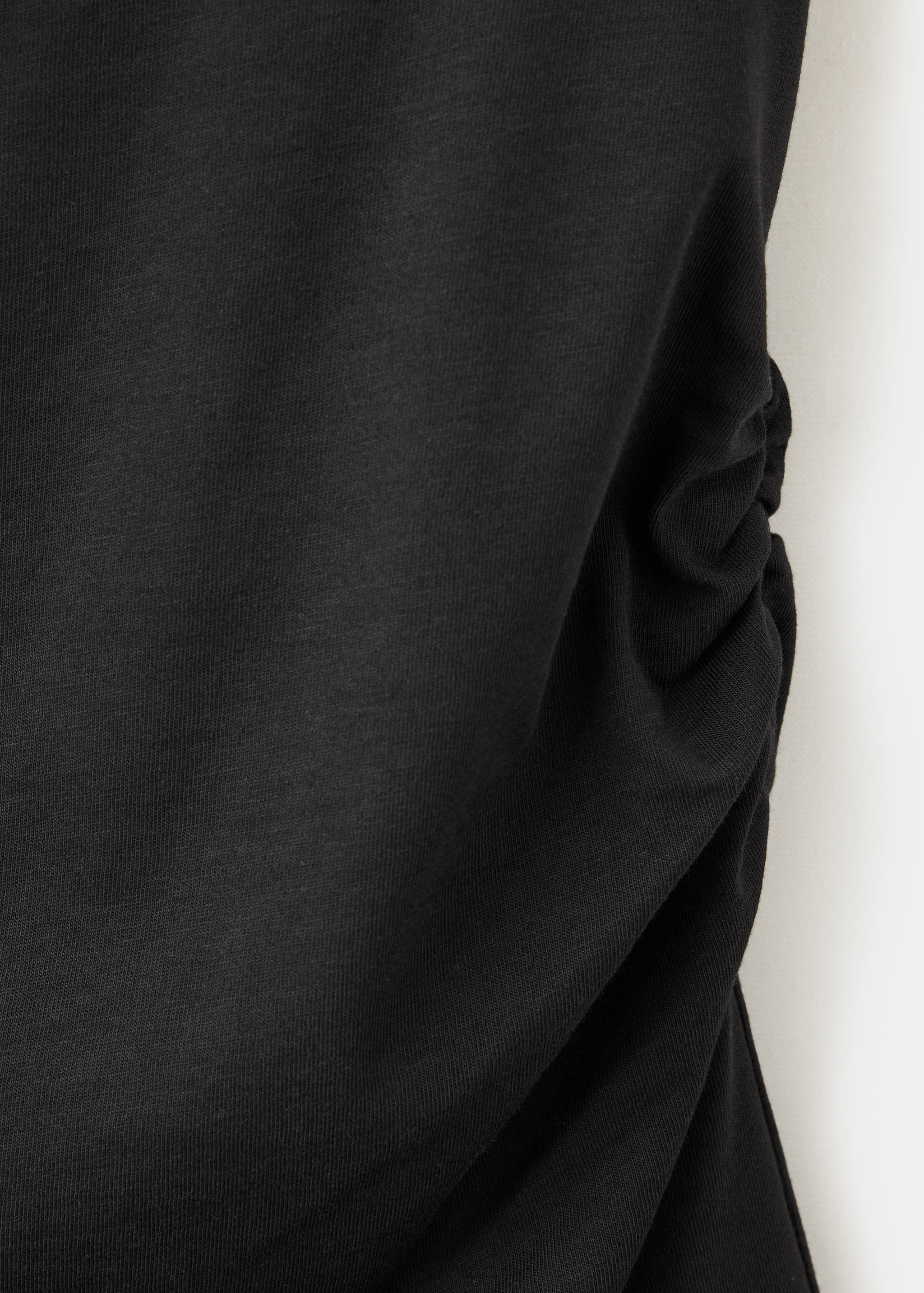 Close-up of a black dress fabric showing ruched side detail.