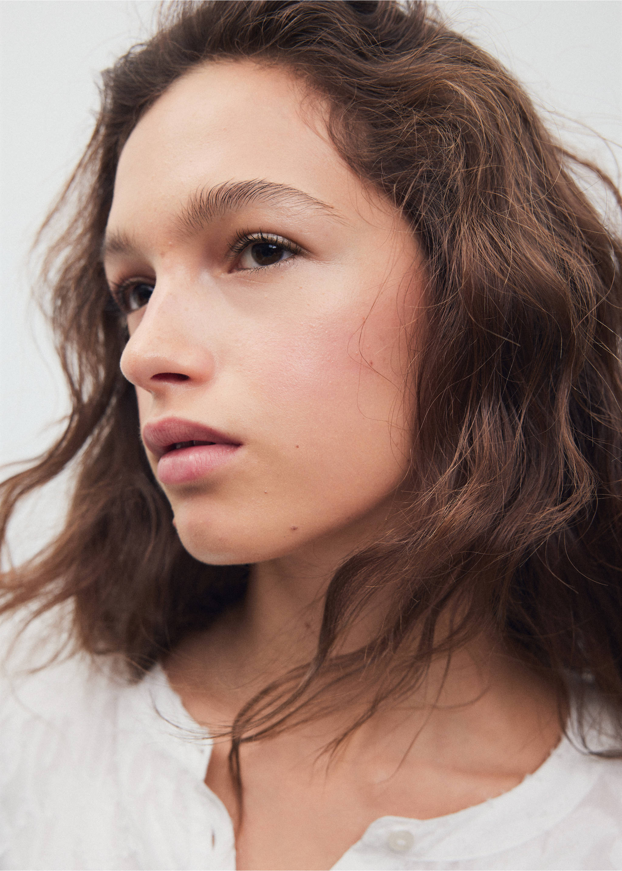 Close-up of a model wearing a white shirt with a buttoned neckline., Off White. Ref: 37038275-00.