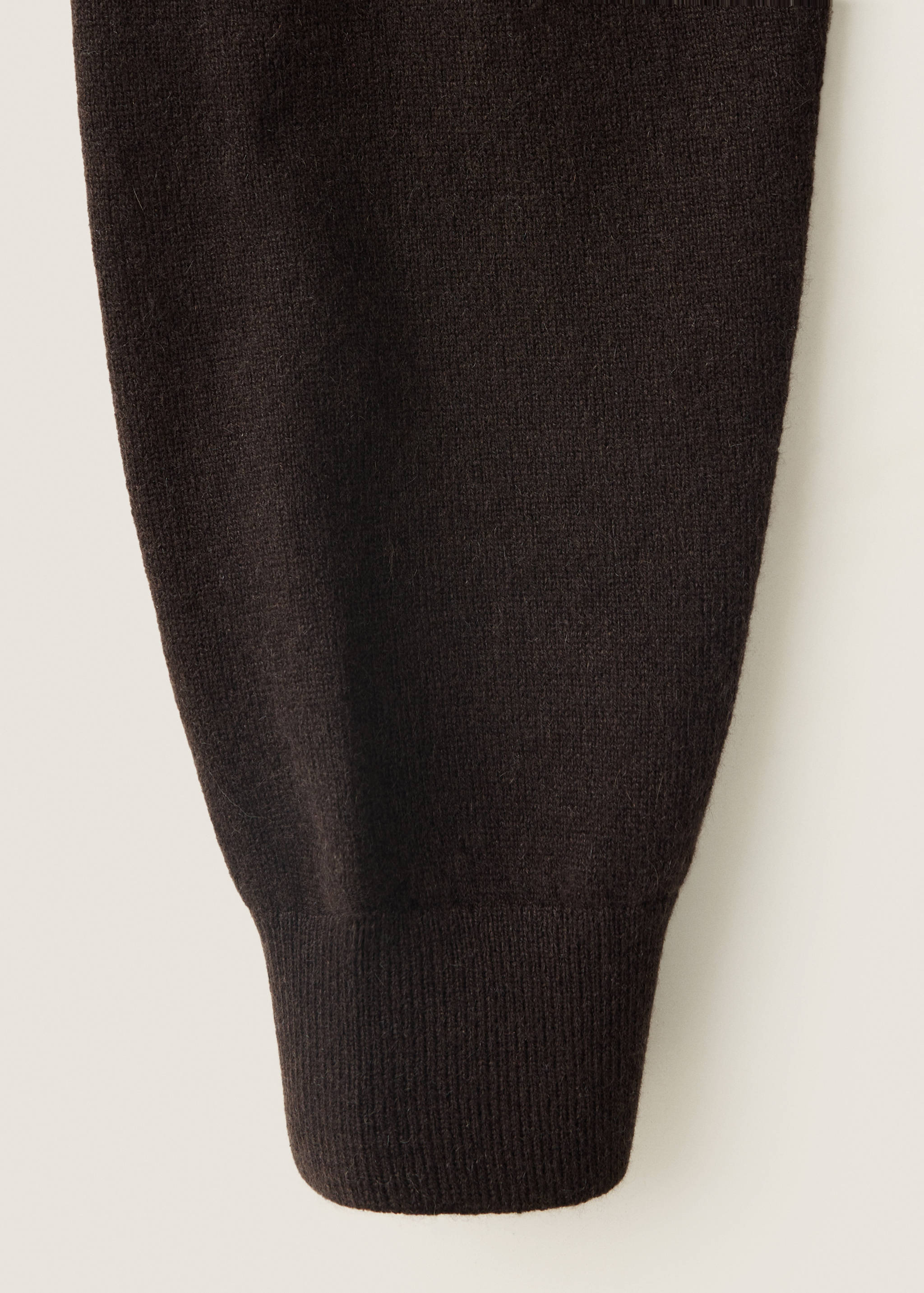 Close-up of the knit texture and ribbed cuff of a dark brown jumper.