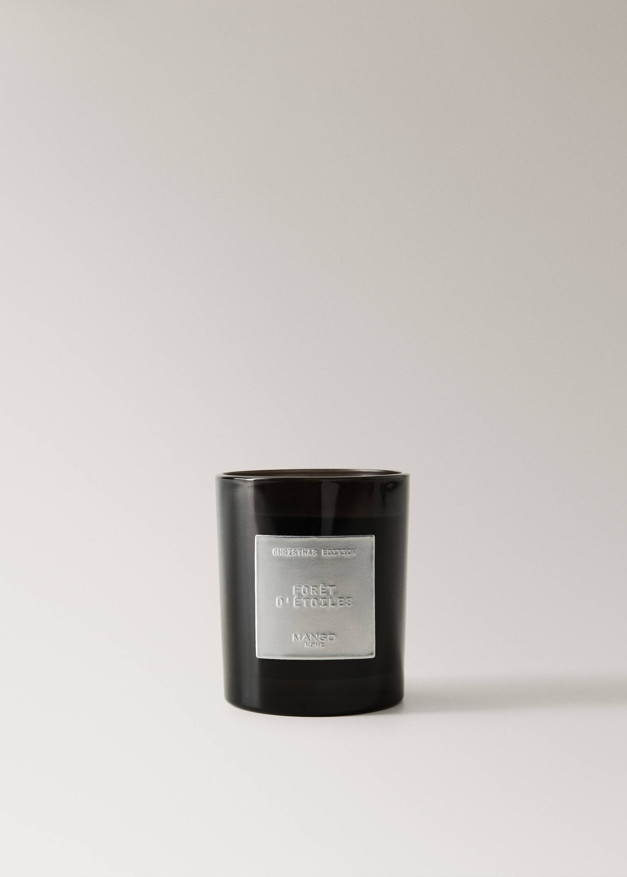Dark scented candle in a glass container with an embossed silver label.