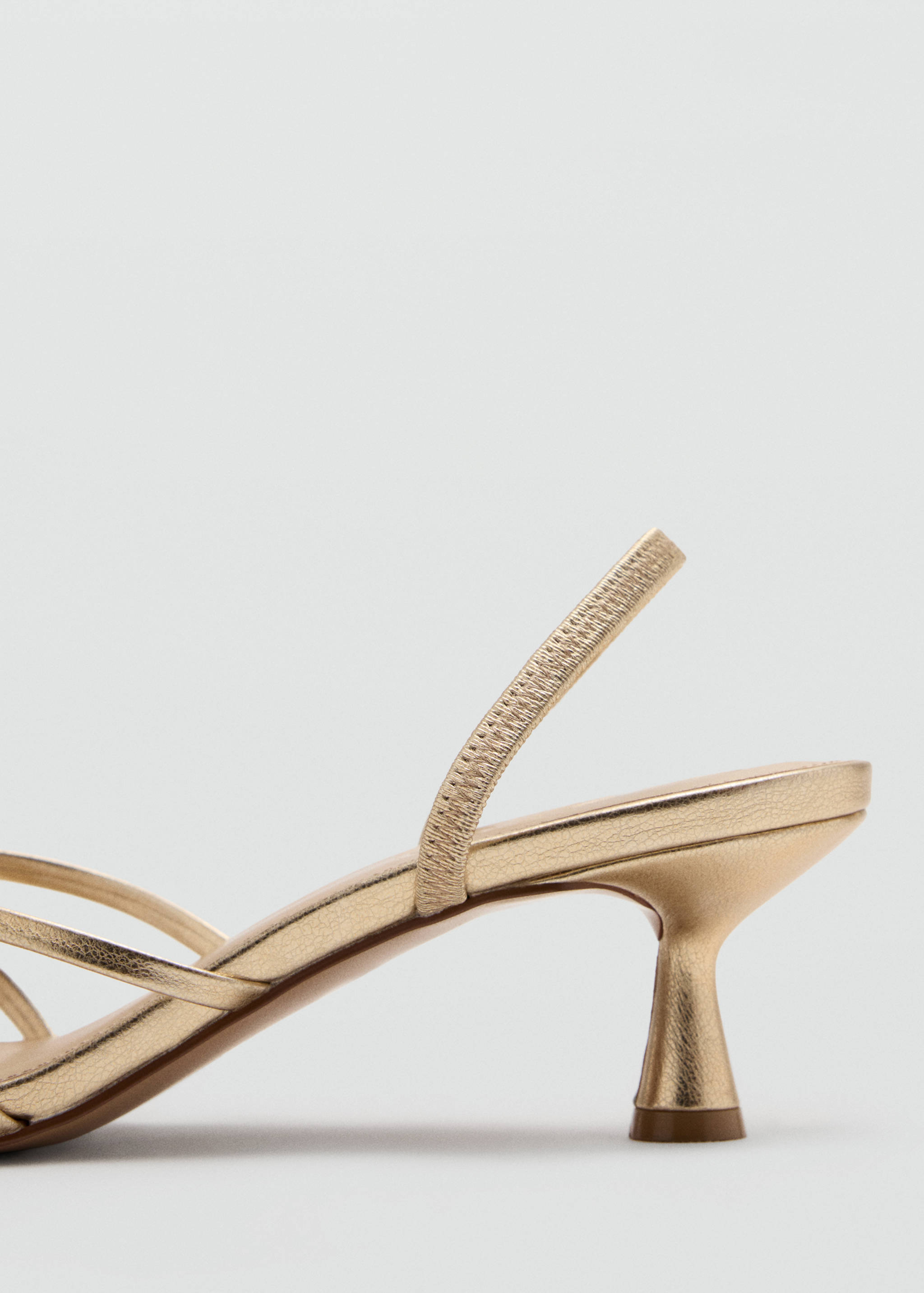 Close-up of a metallic gold sandal with a slender kitten heel.