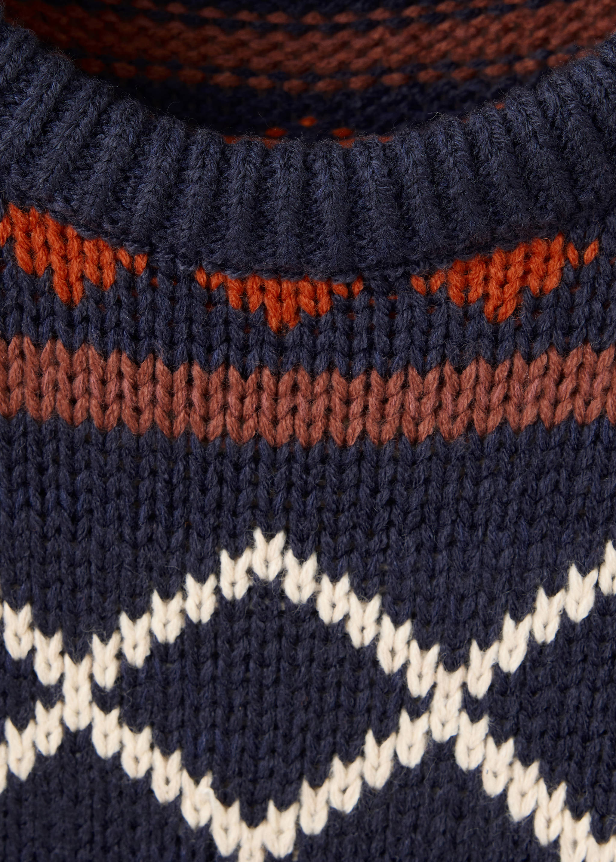 Navy blue knitted children's jumper with a fair isle neckline and cream diamond pattern.