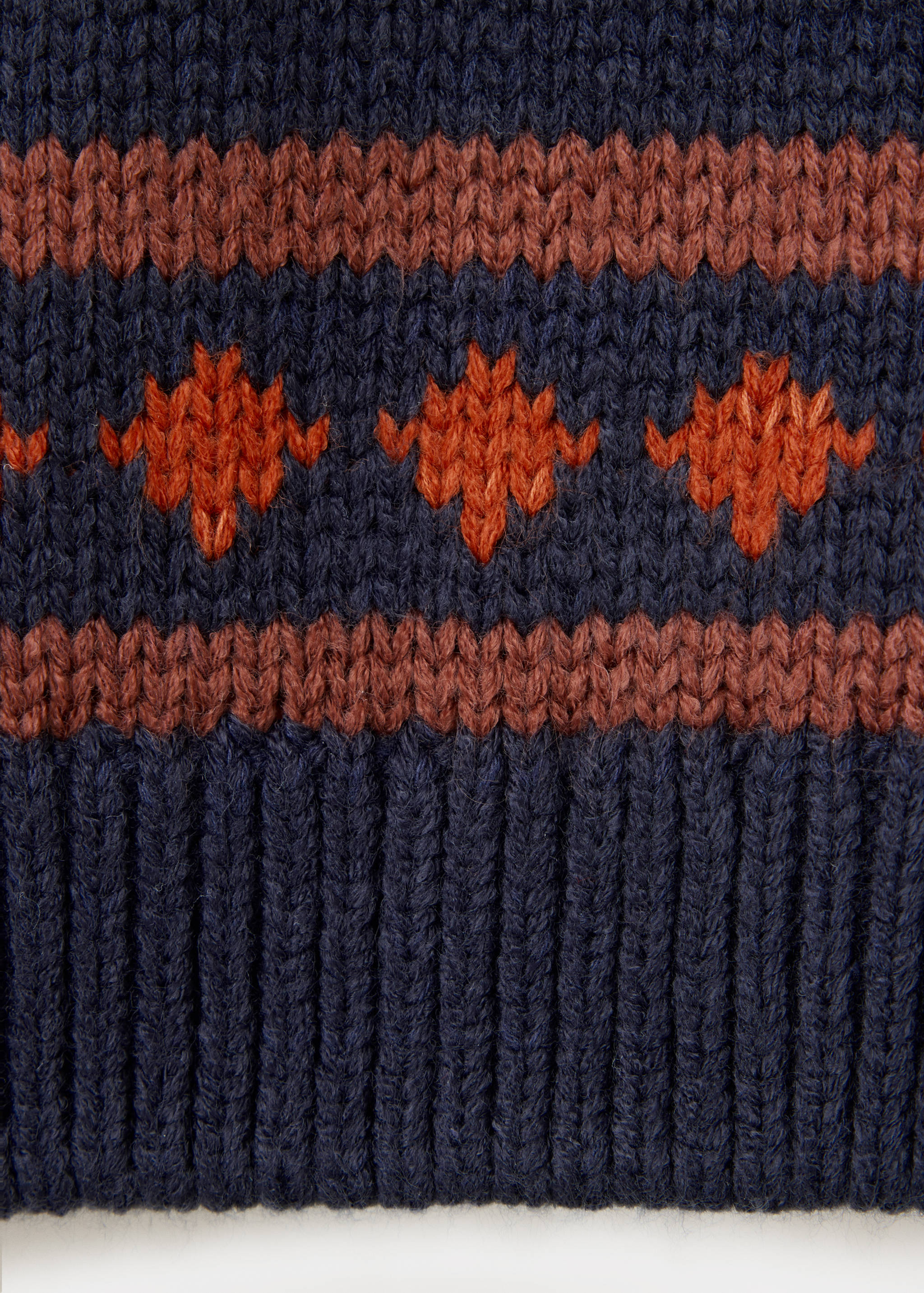 Navy blue children's jumper fabric detail with ribbed hem and orange geometric knit pattern.
