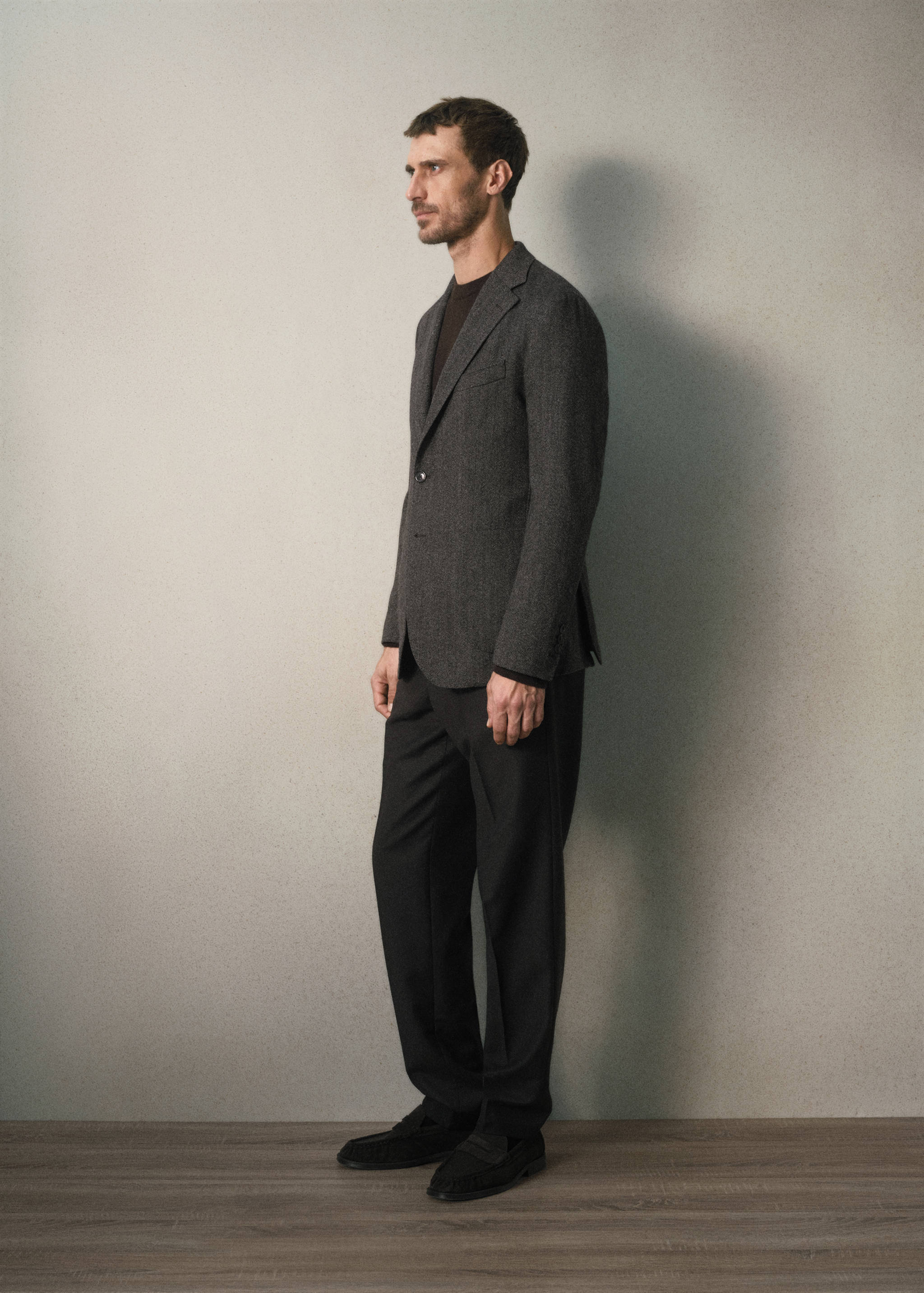 Dark grey textured single-breasted blazer worn with dark trousers.