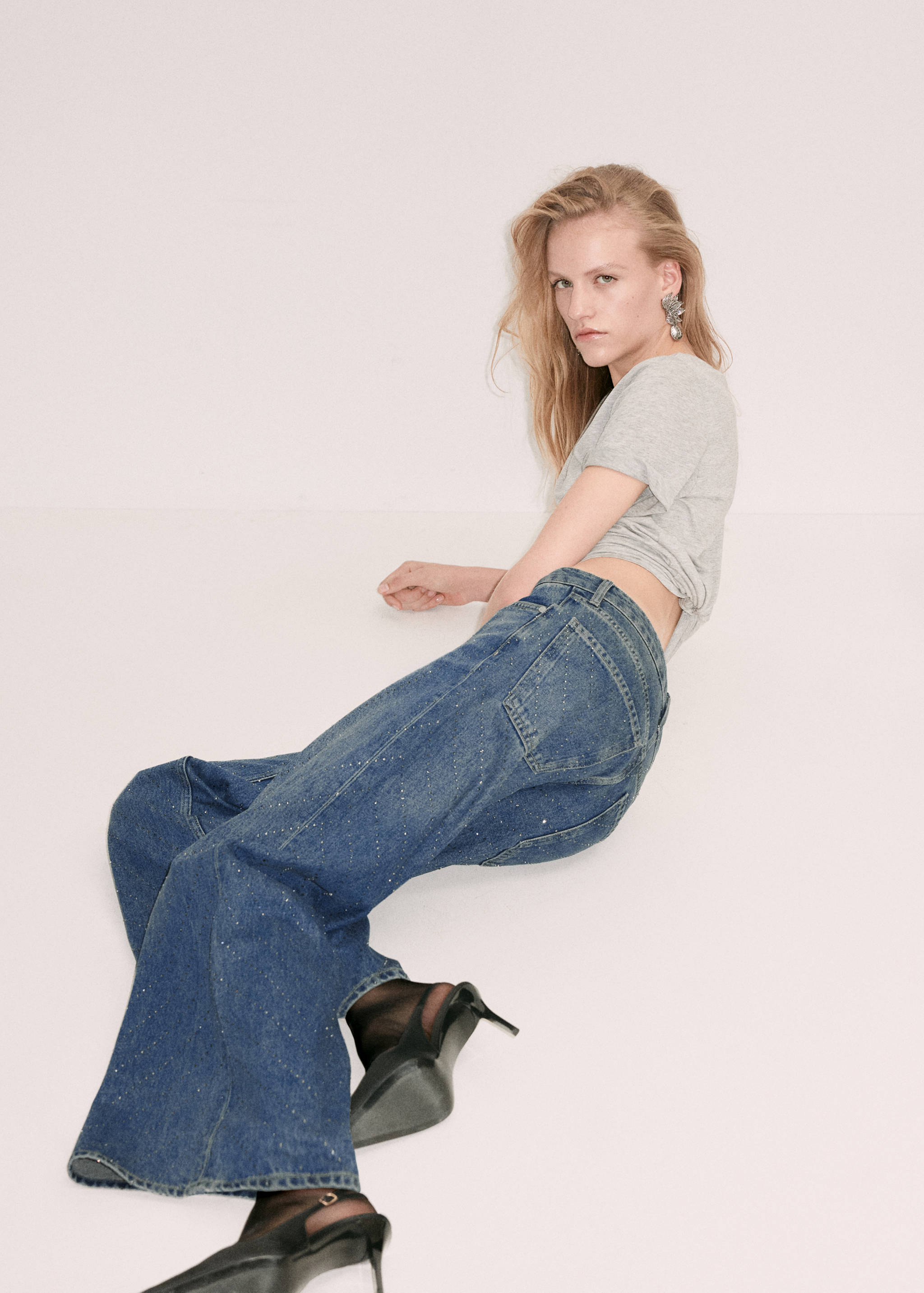 Blue denim trousers with rhinestone embellishments, worn with a grey t-shirt.