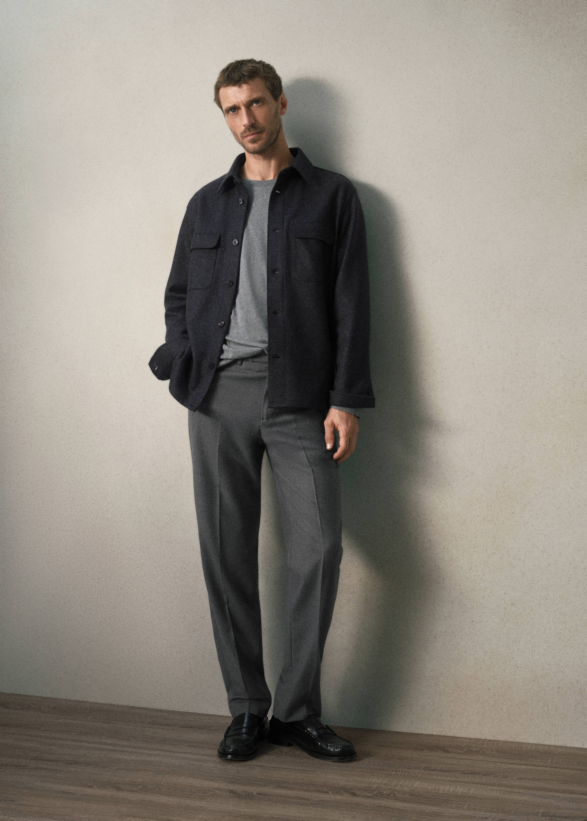 Grey t-shirt worn with a dark grey overshirt and grey trousers.