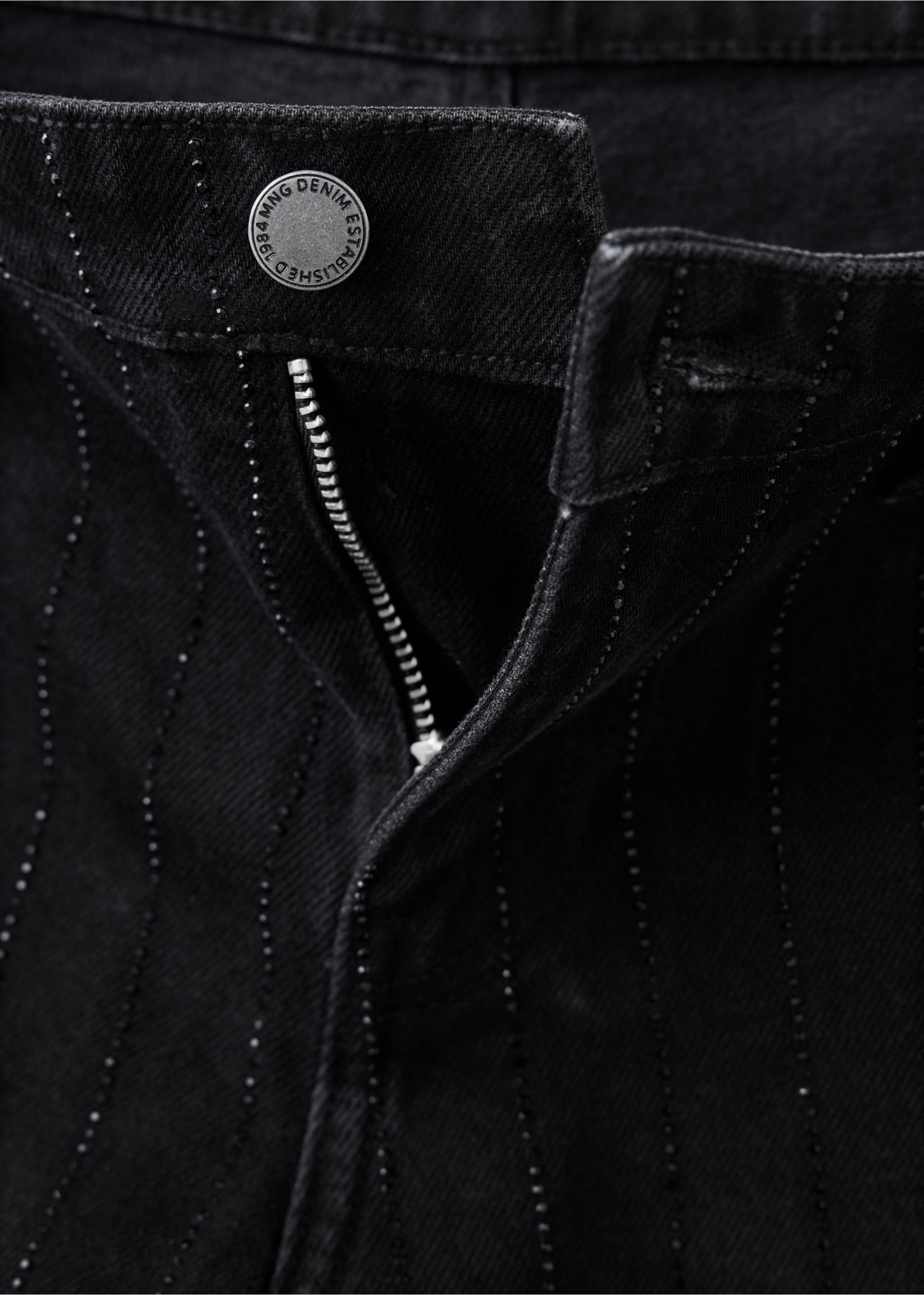 Primer plano de pantalones vaqueros negros con bragueta de botones y aplicaciones de pedrería verticales., Denim negro. Ref: 37039116-00.
