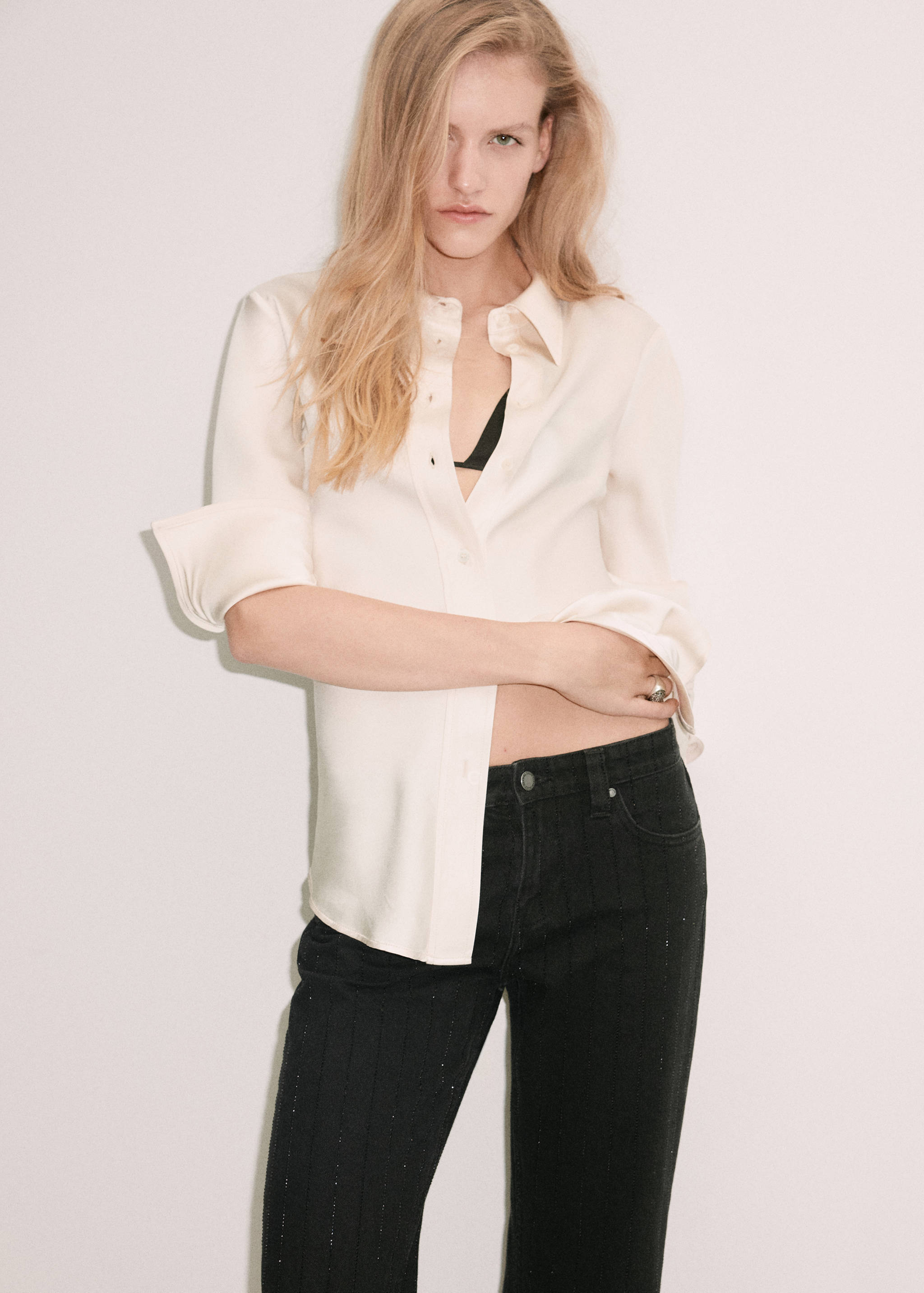 Black denim trousers with subtle vertical stripes, worn with a cream silk shirt.