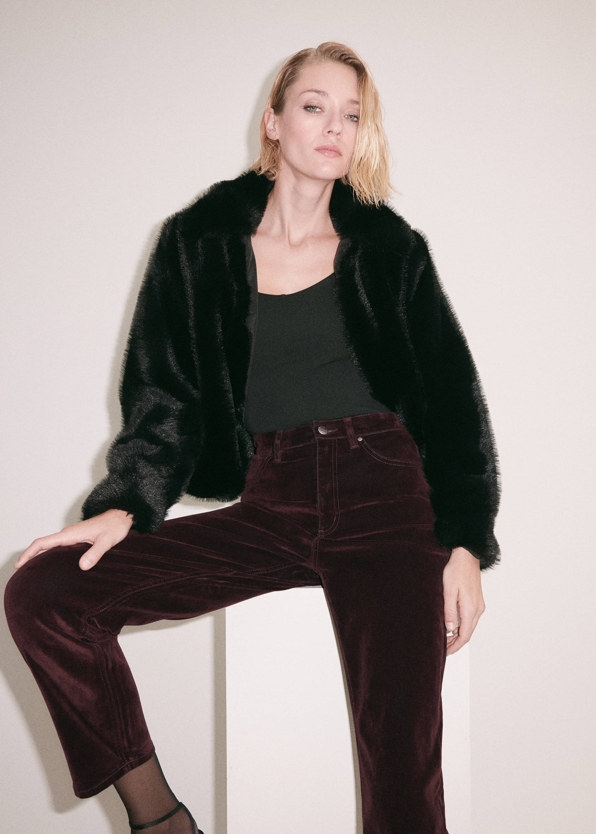 Pantalones de terciopelo burdeos combinados con una chaqueta efecto pelo negra.