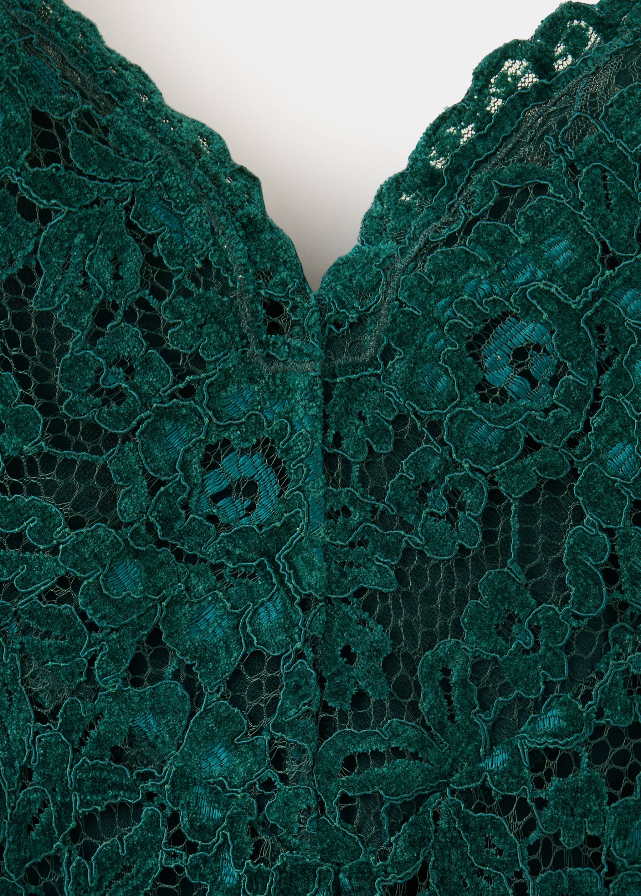 Dark green lace dress detail showing the floral pattern and neckline.