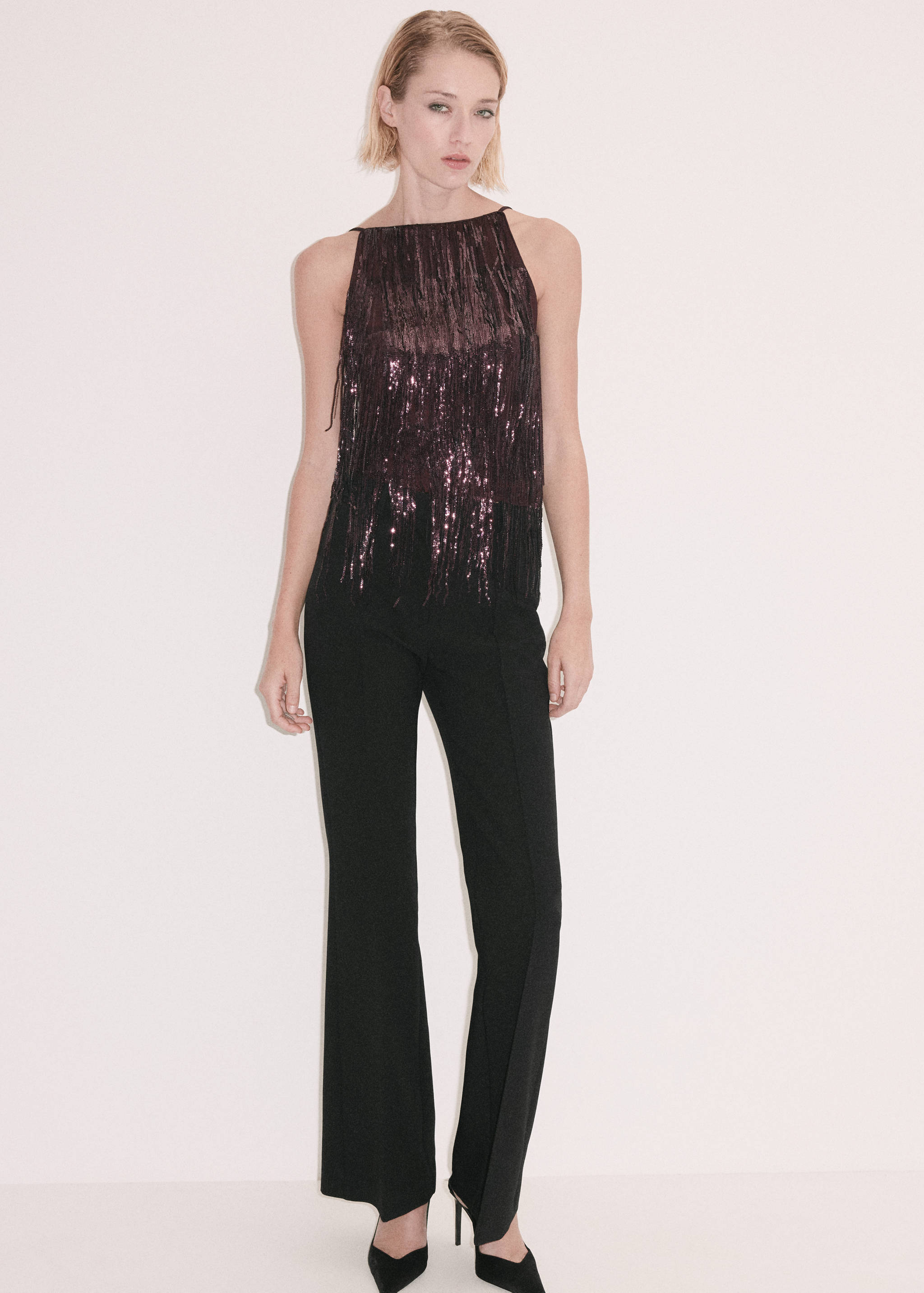 Burgundy sequin fringe top with a square neckline and thin straps, worn with black trousers.