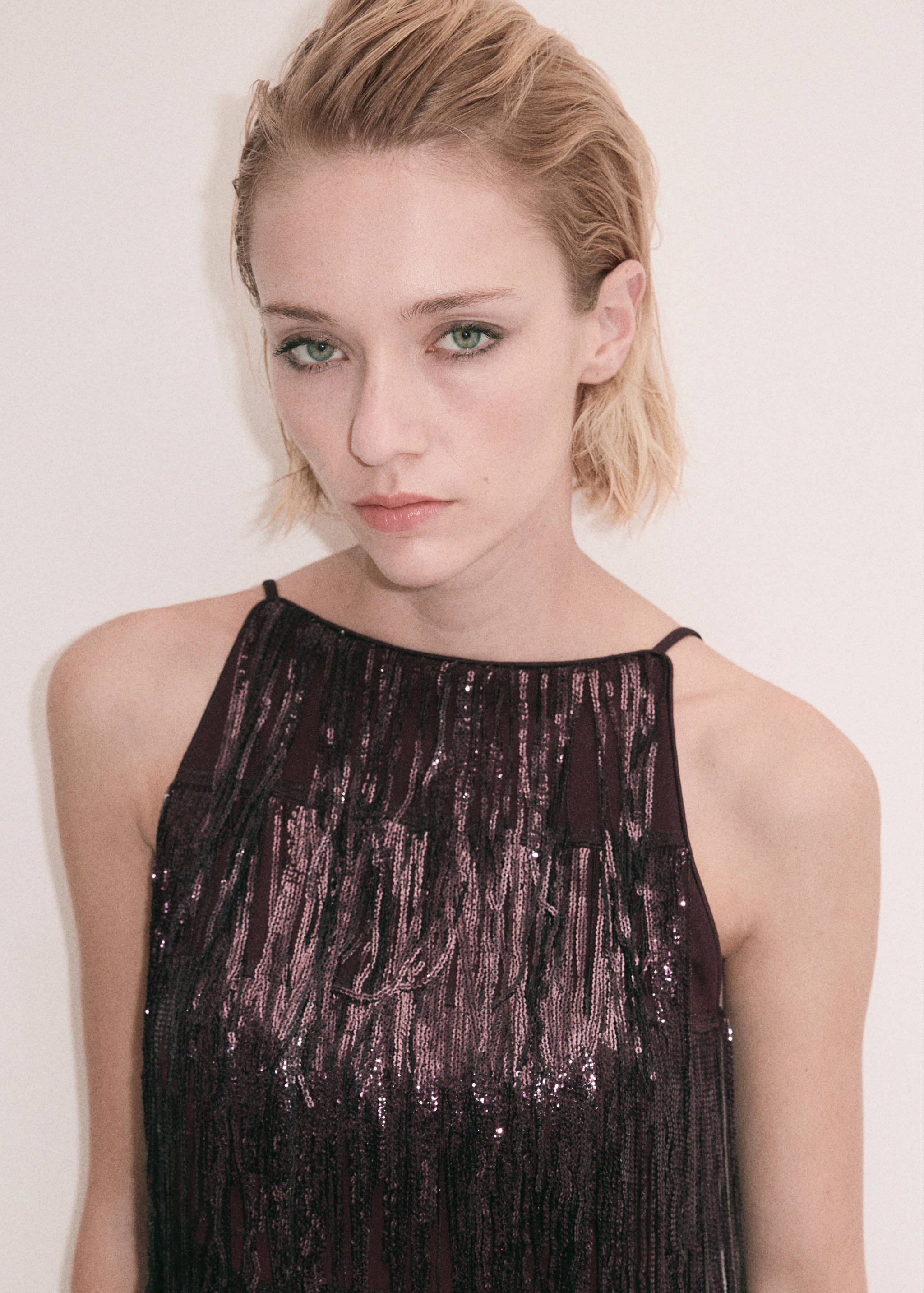 Close-up of a dark plum sequinned halter top with thin straps.