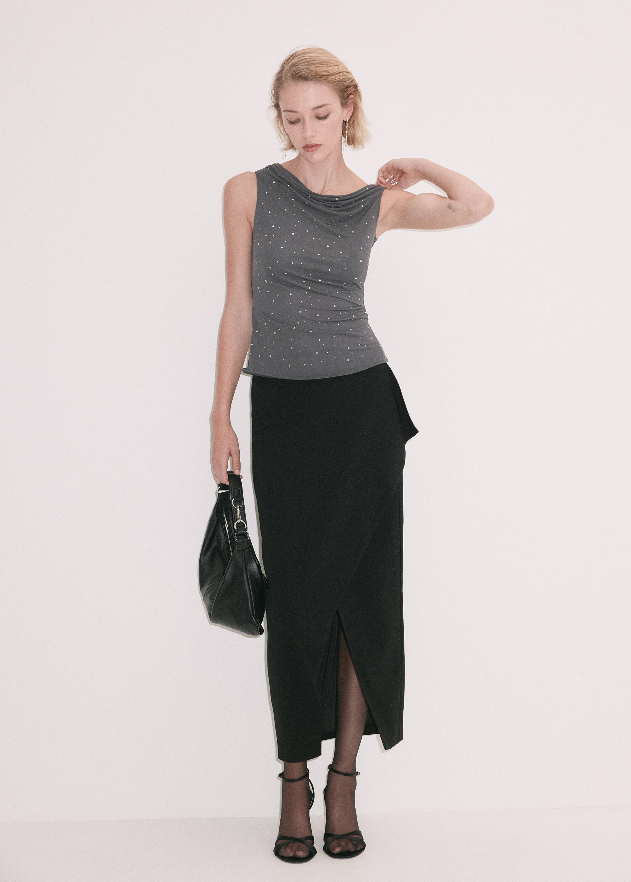Dark grey sleeveless top with cowl neckline and rhinestones, styled with a black skirt.