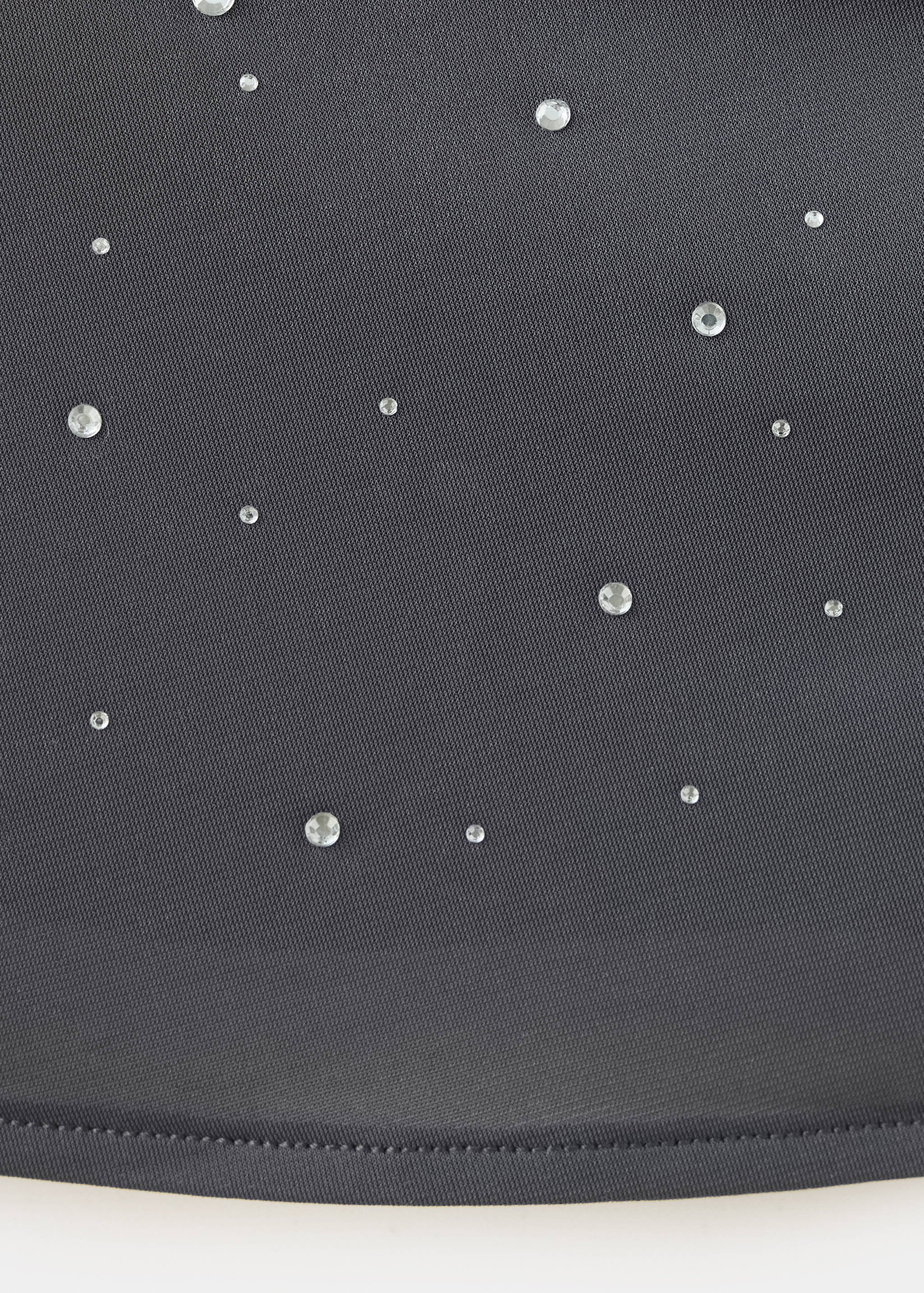 Close-up of a dark grey rhinestone-embellished top fabric.