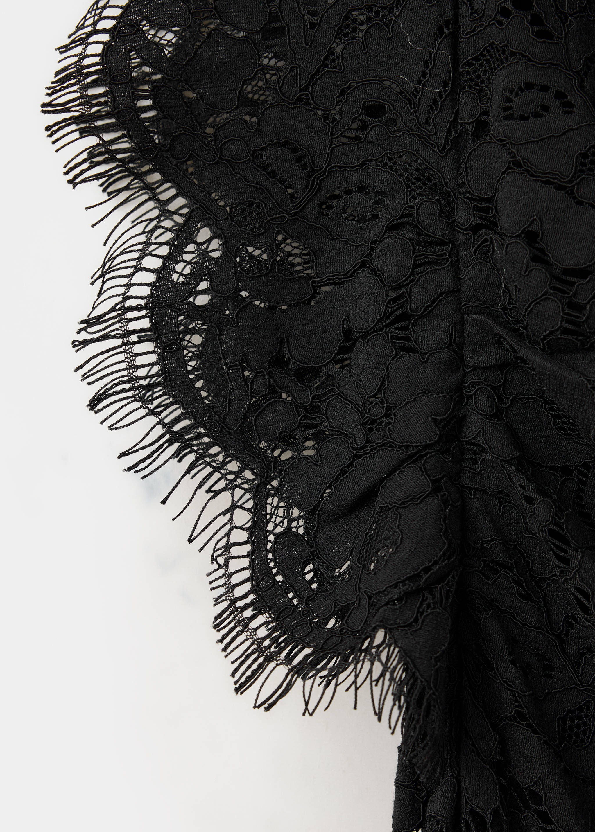 Close-up of black lace dress with scalloped eyelash fringe trim.
