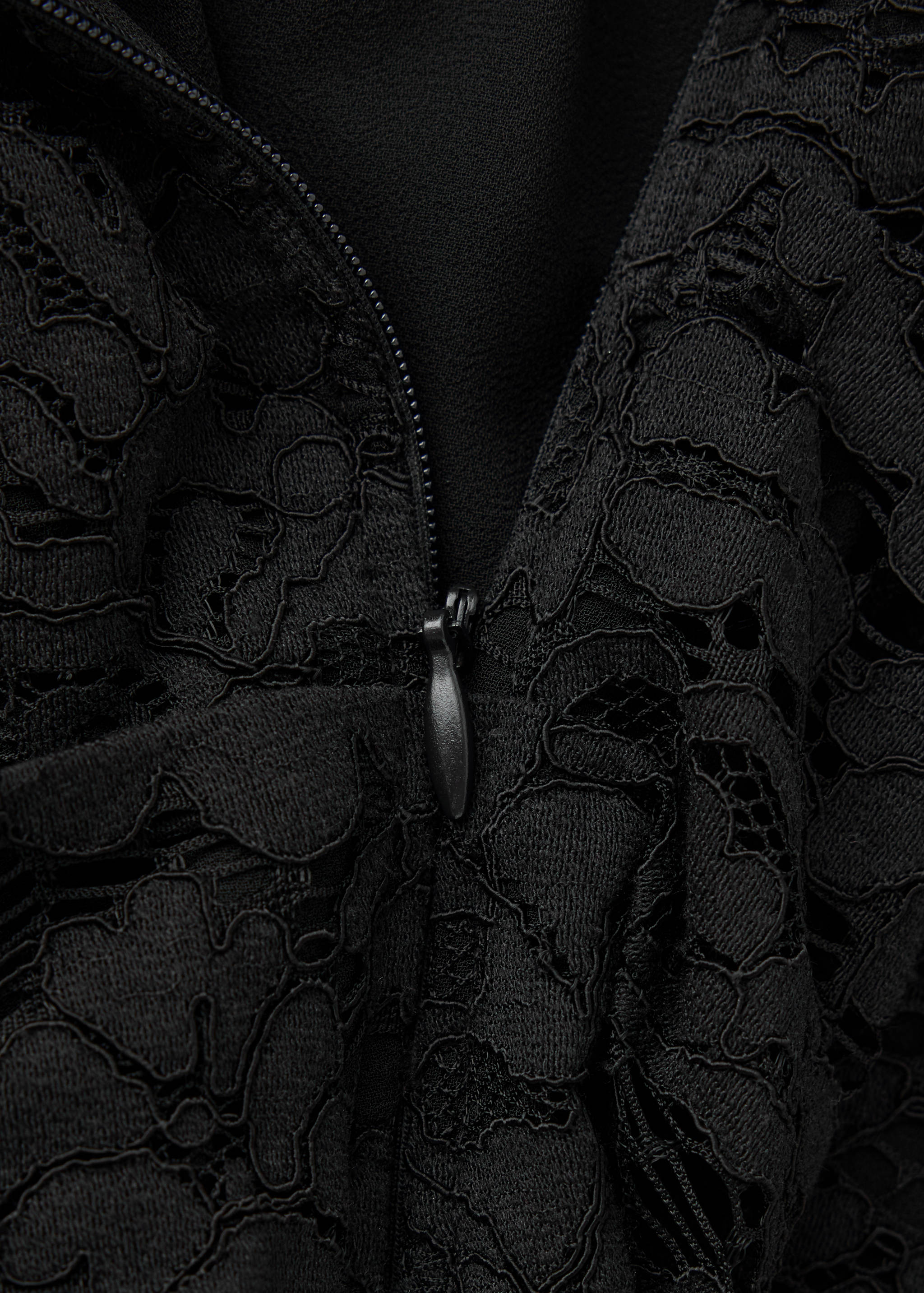 Close-up of black lace dress showing fabric texture and zip.