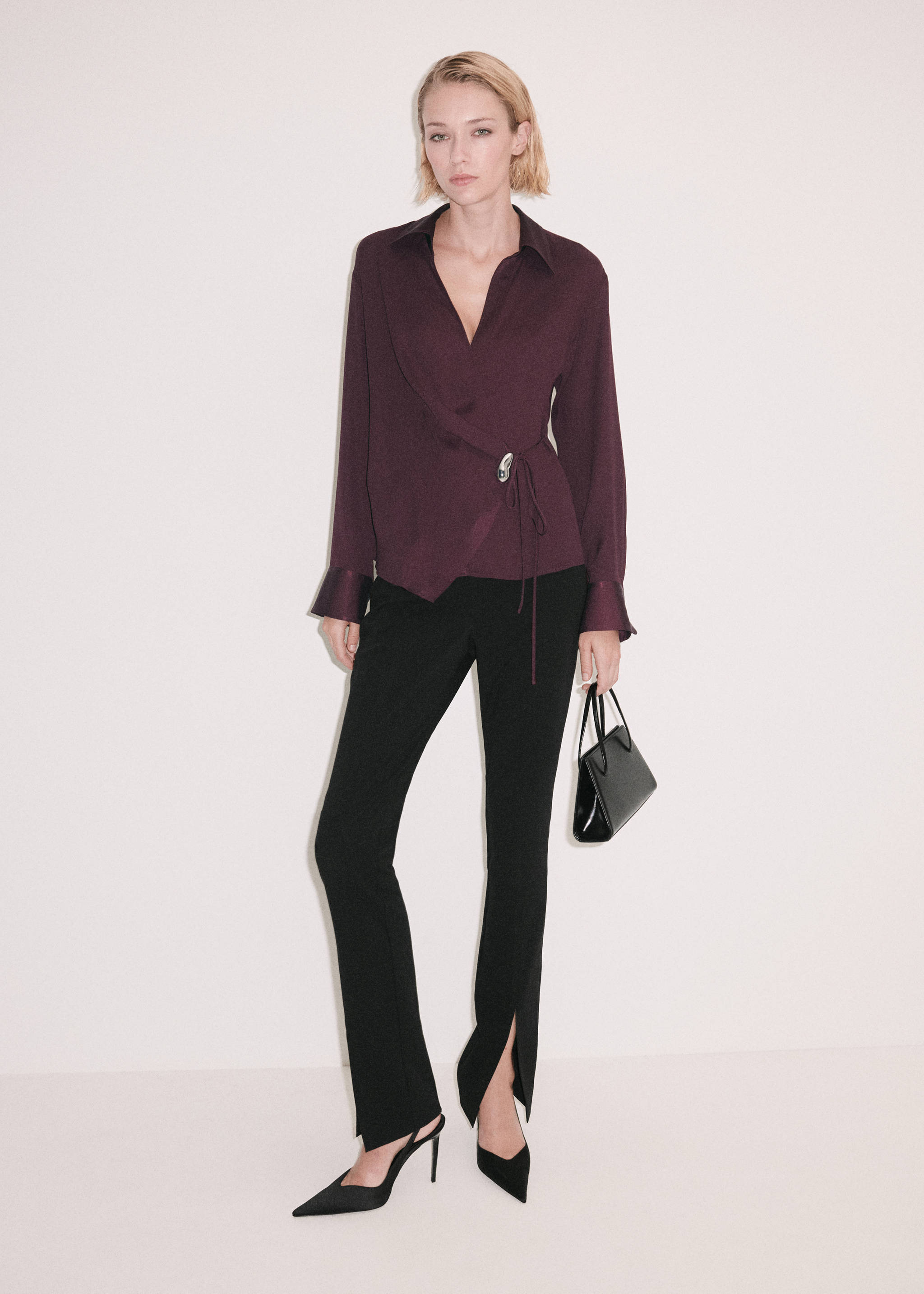 Dark plum wrap shirt with a silver buckle, worn with black trousers.