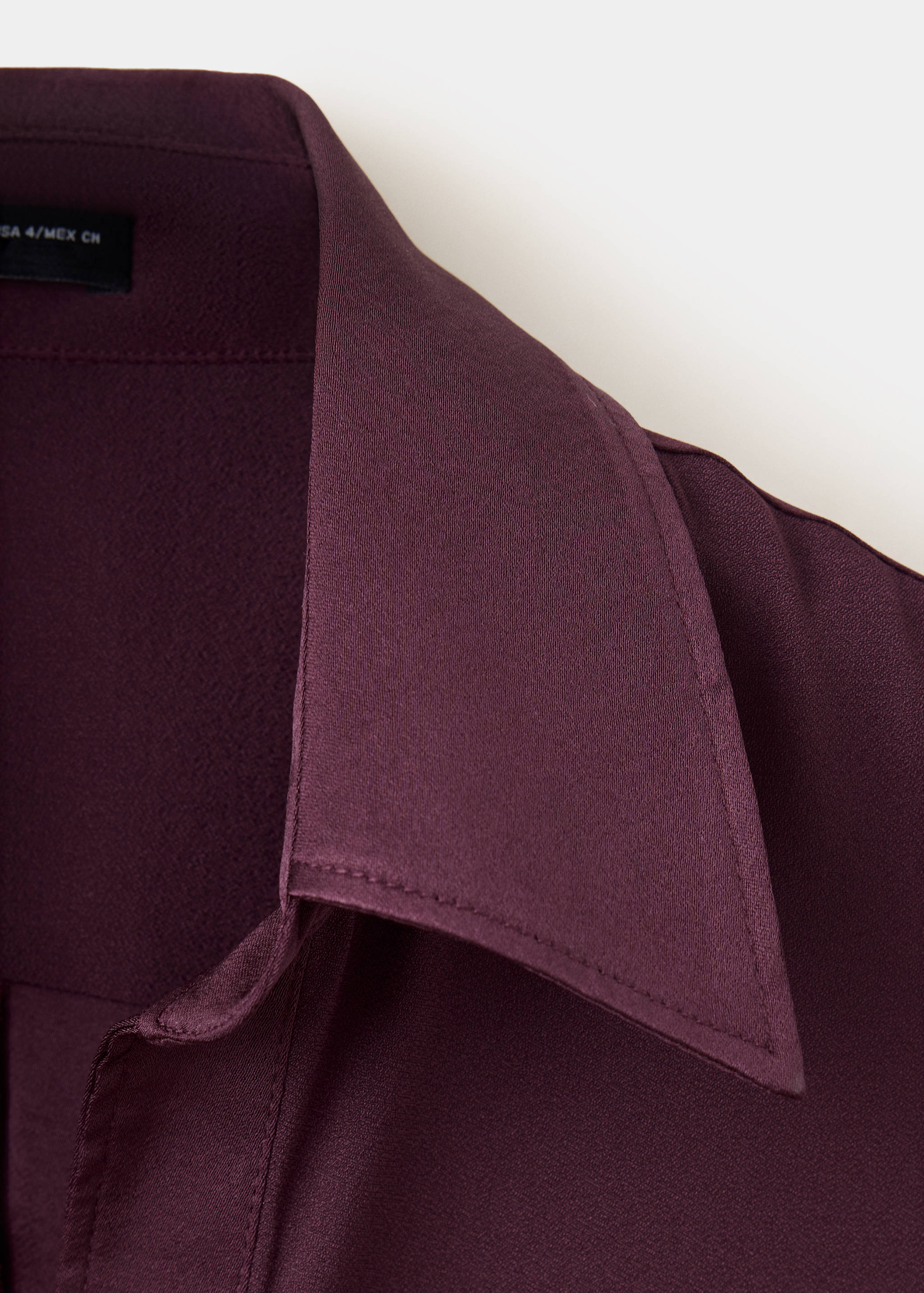 Plum shirt collar close-up with topstitching detail.